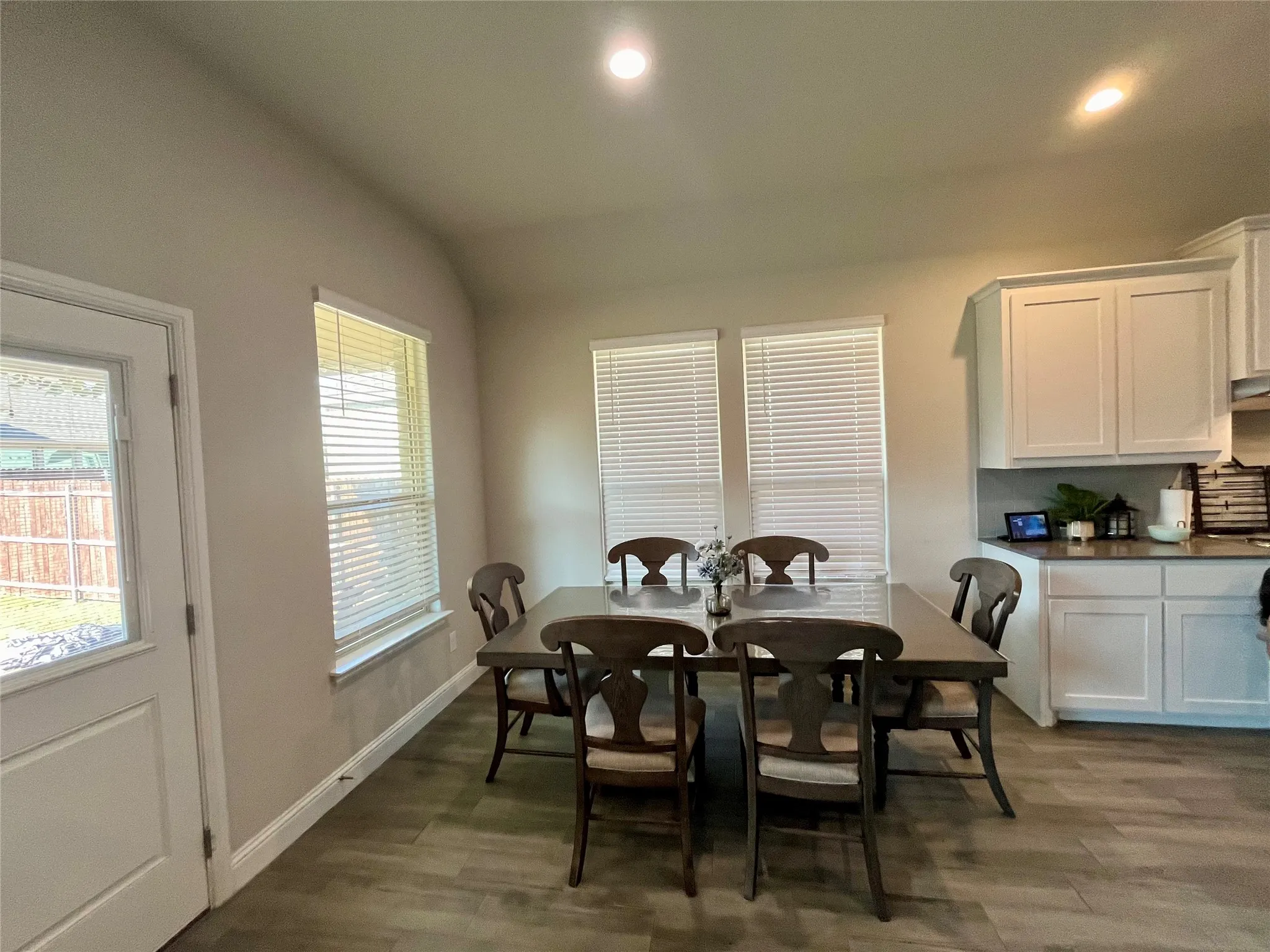 Wood-finish flooring, recessed lighting, white cabinetry, and multiple windows with blinds