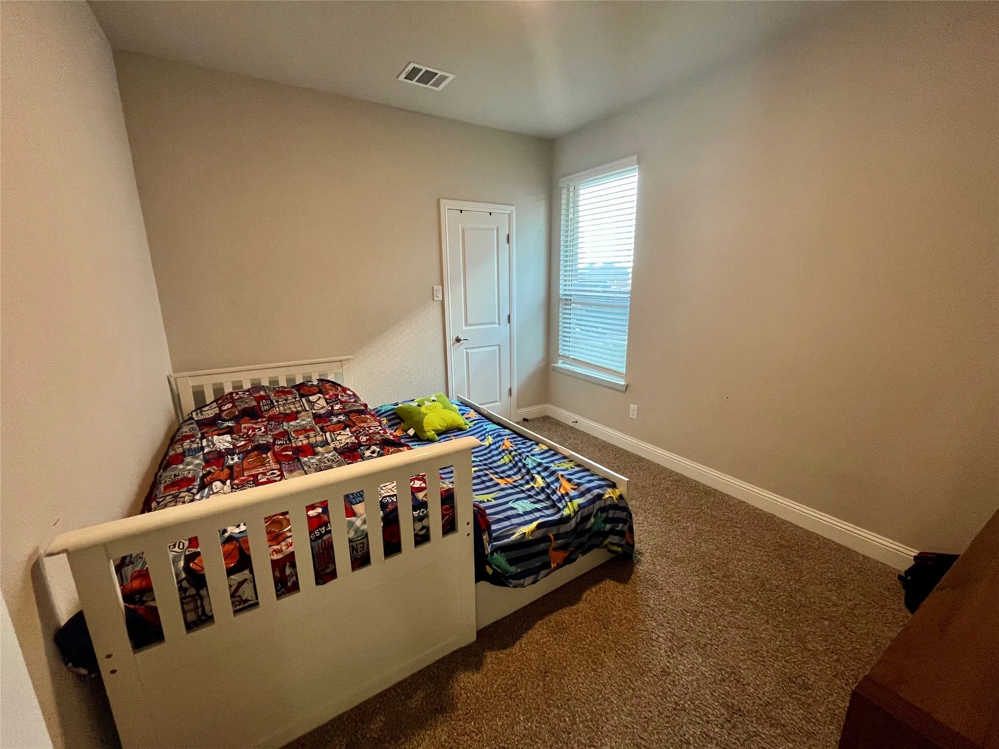 Neutral wall paint, window with horizontal blinds, white trim, and brown carpet