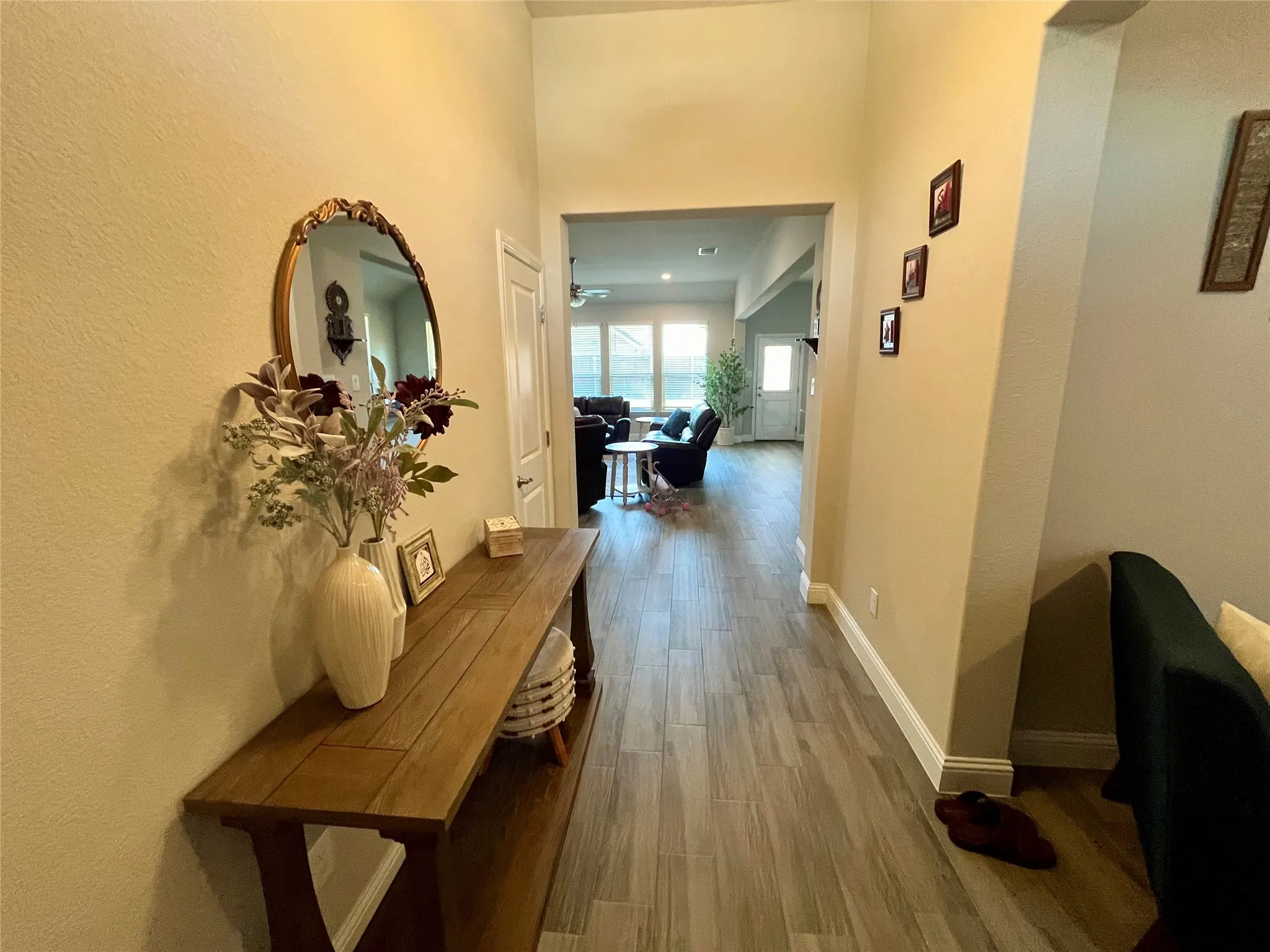 Hallway featuring light-toned walls, wood-finish flooring, and white trim