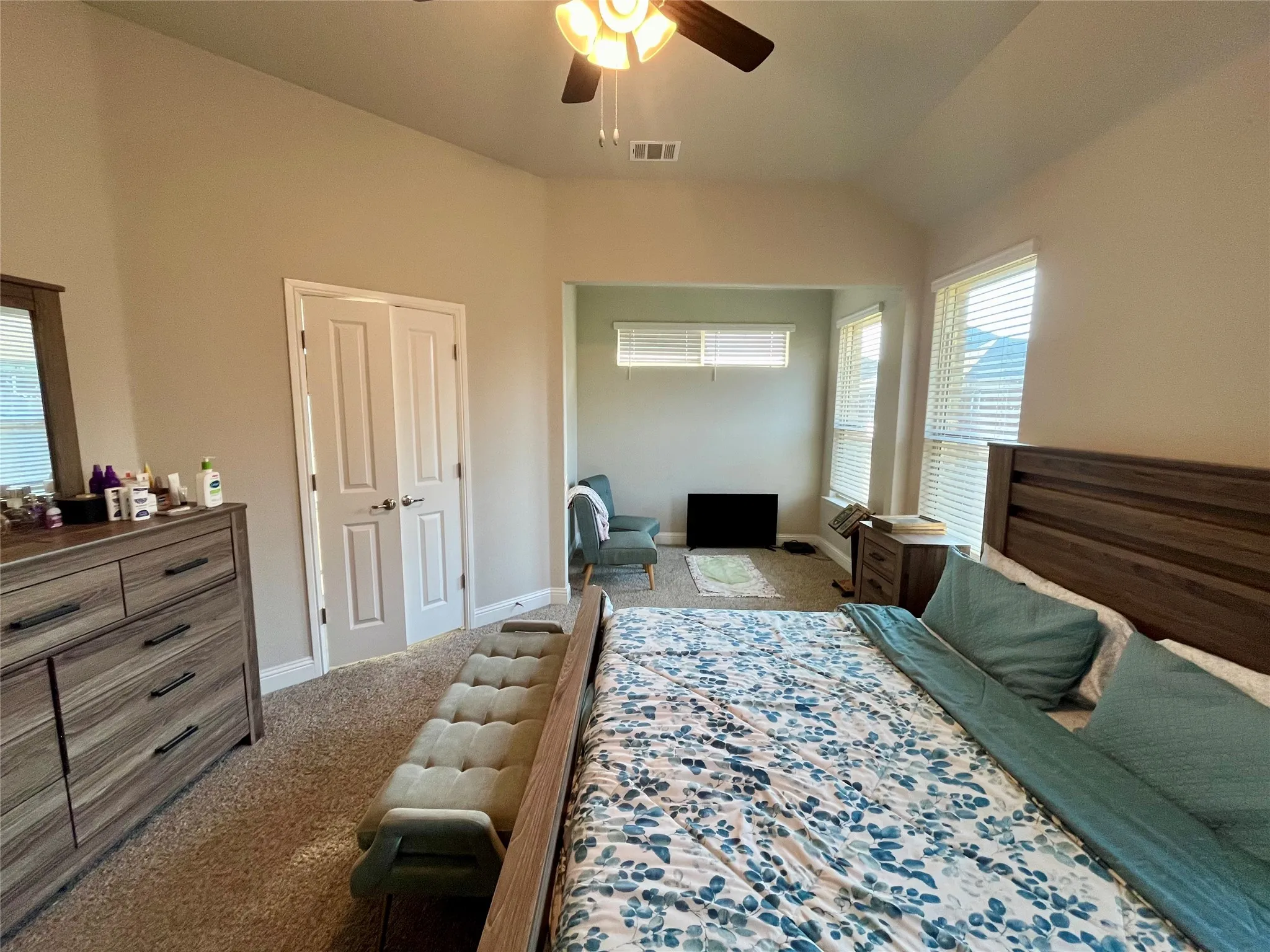Large master with Recessed alcove with multiple windows, vaulted ceiling, and ceiling fan with integrated lighting