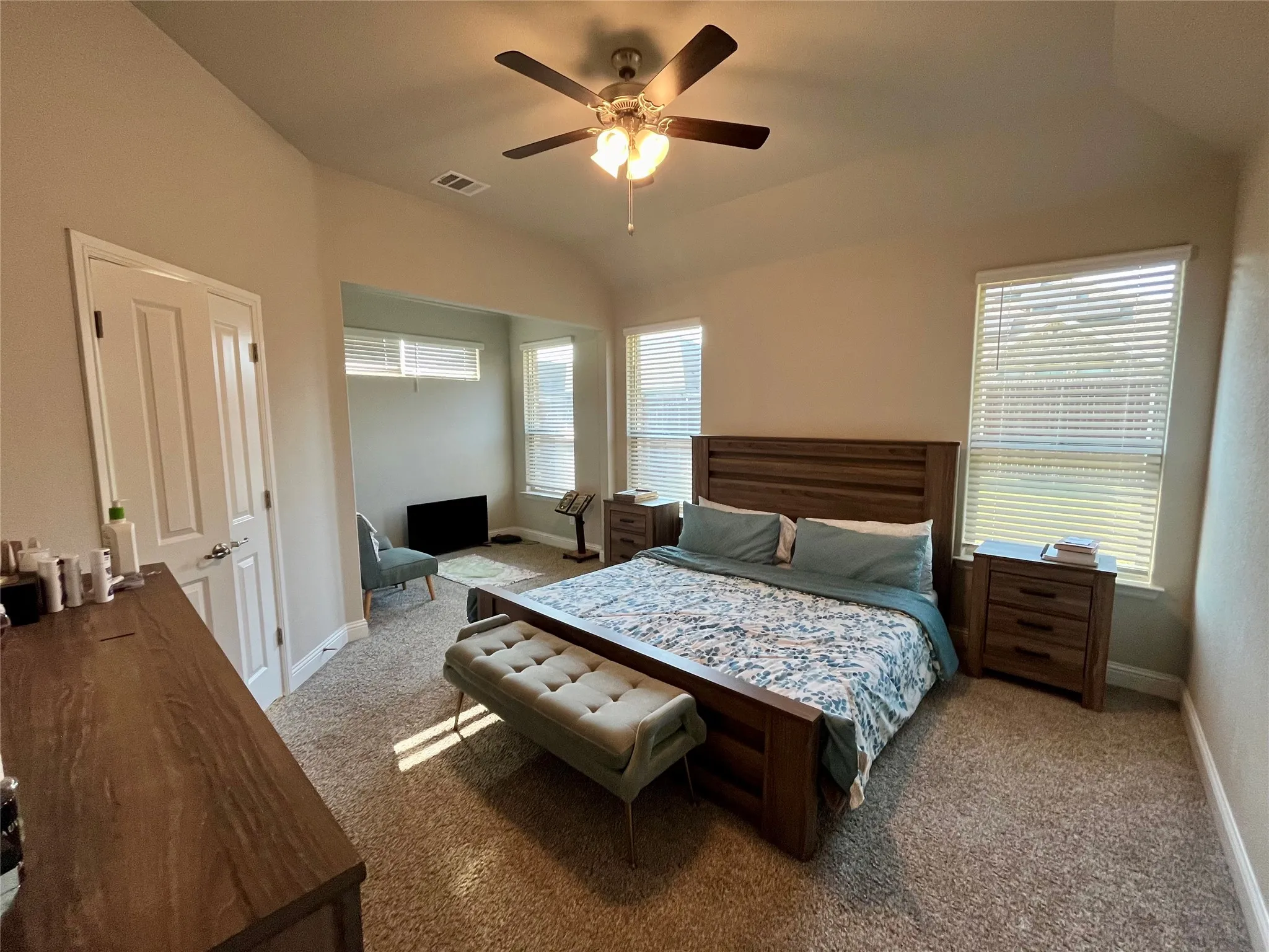 Room features vaulted ceilings, a ceiling fan with integrated lighting, and carpet flooring