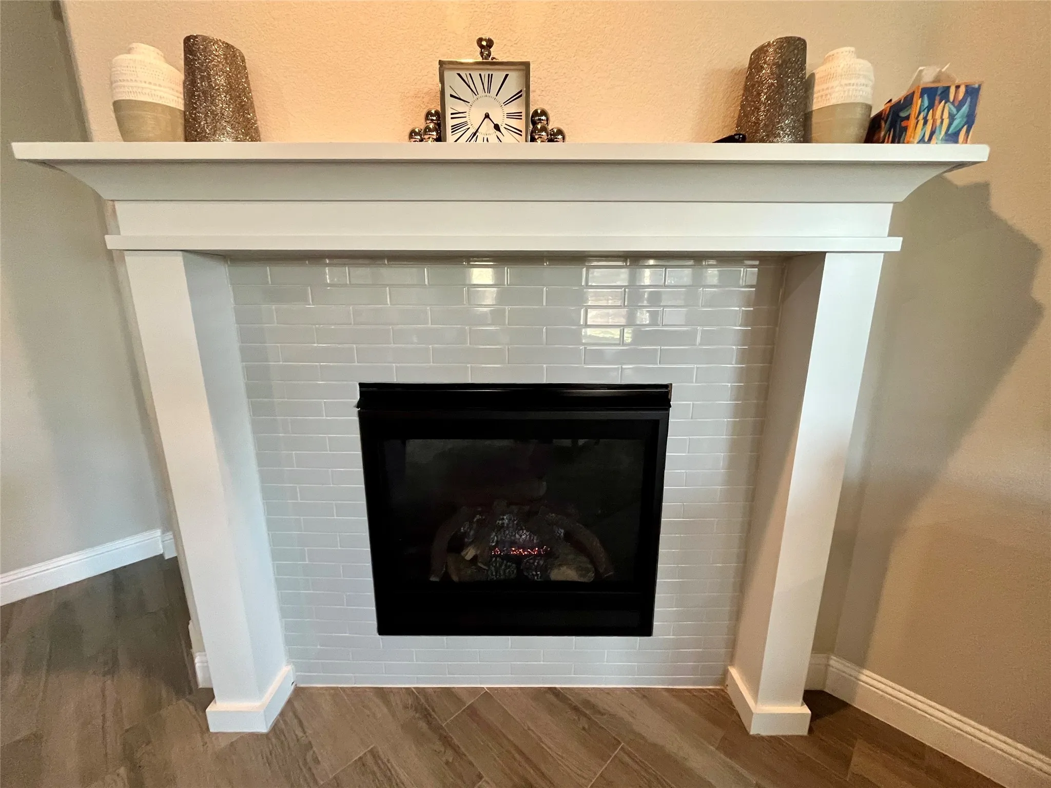 Fireplace with a white mantel, gloss subway tile surround, and black firebox