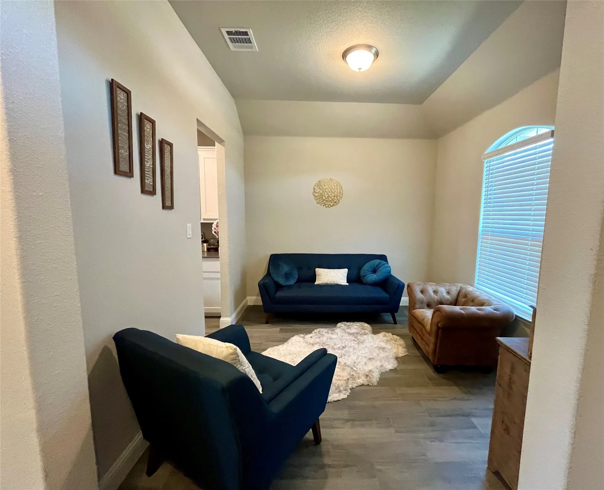 Tray ceiling with recessed lighting, arched window, and wood-finish flooring