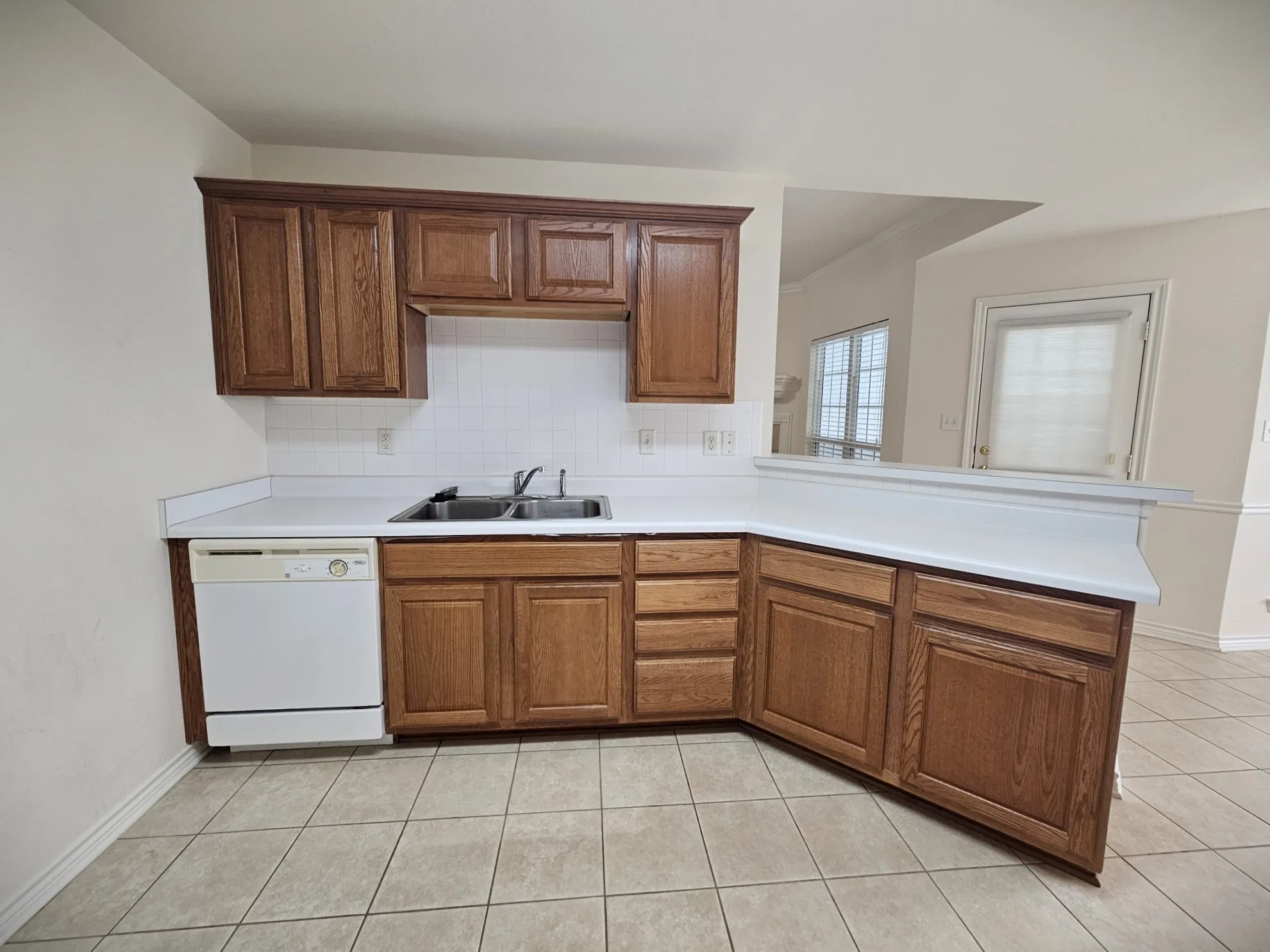 Kitchen featuring wood-finish cabinetry, white countertops, tile flooring, and white appliances
