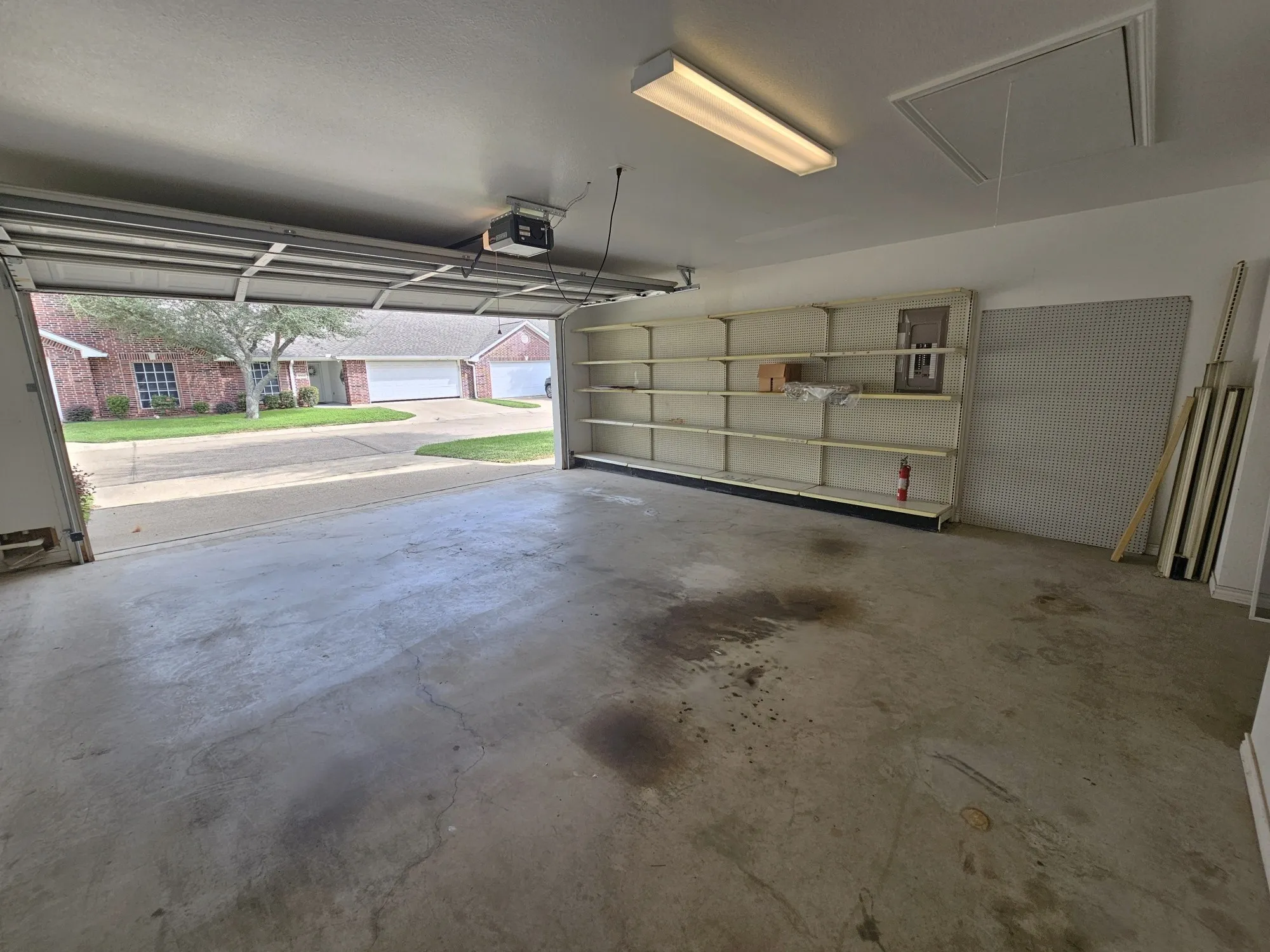 Attached garage with a concrete floor, built-in shelving, and white paneled garage door