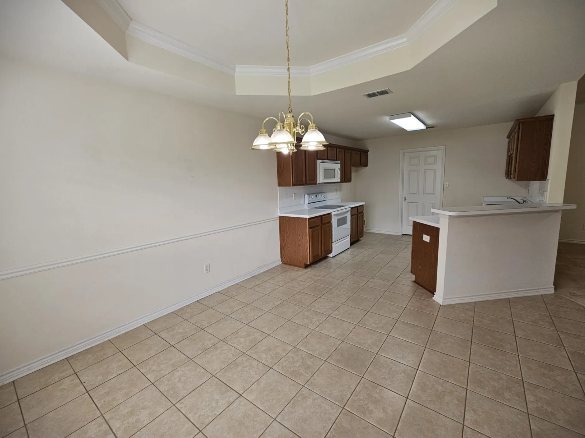 Wood-finish cabinetry, white countertops, a double basin sink, and a white dishwasher