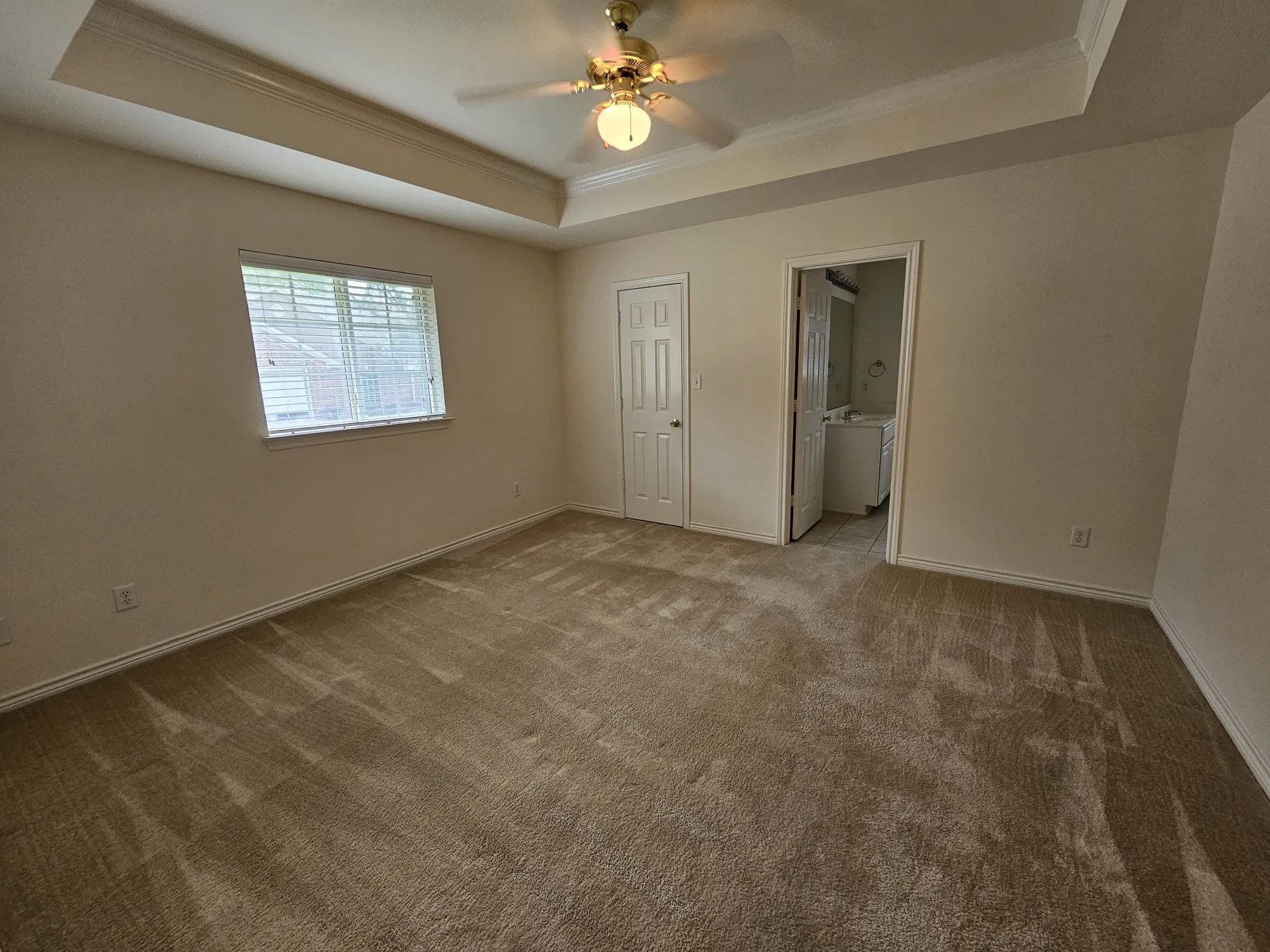 Recessed ceiling detail with crown molding, ceiling fan with light fixture, and neutral carpeted flooring