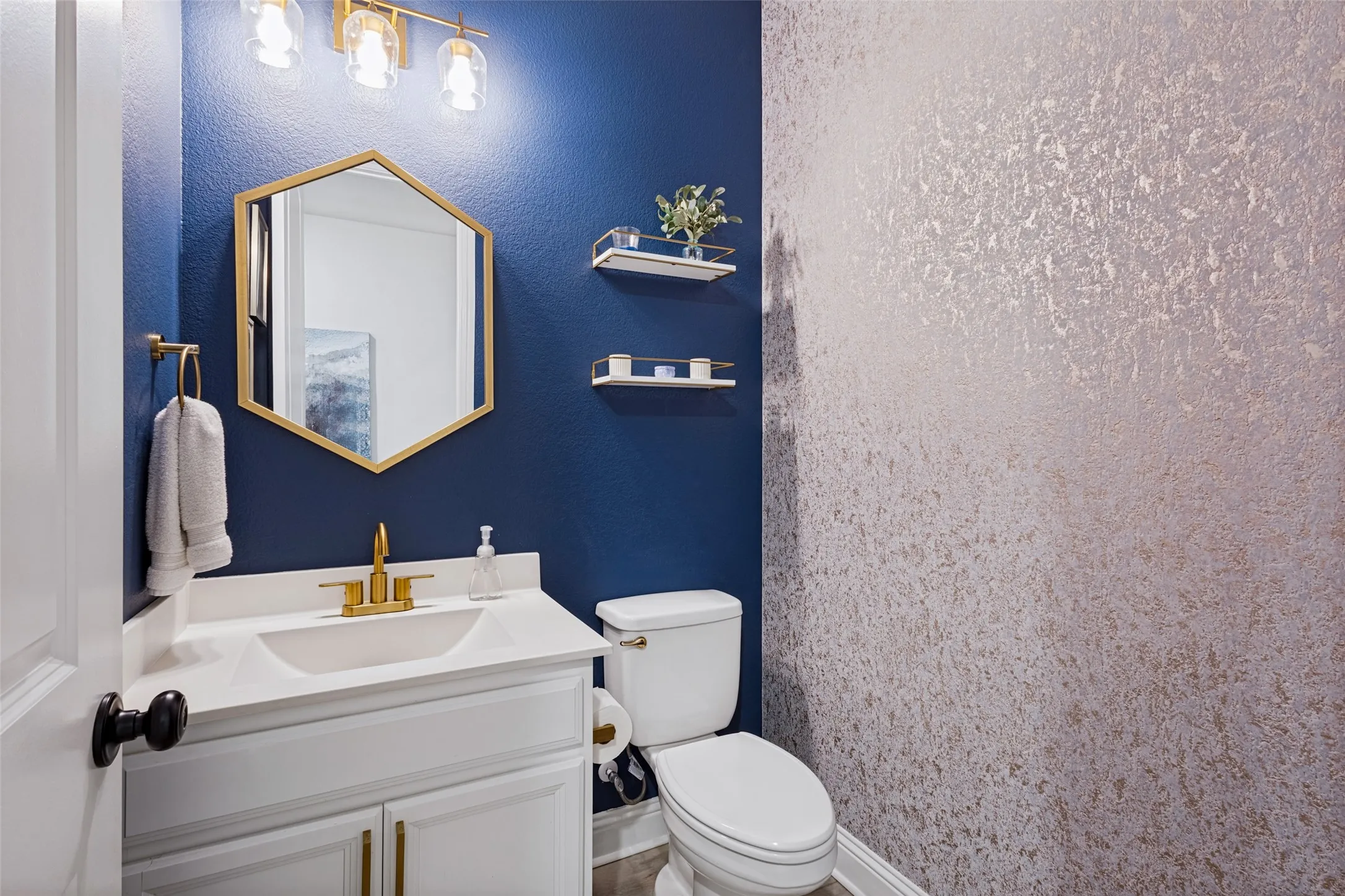 Updated half bathroom located near kitchen. Fresh paint and wall paper. Updated Hardware, lighting, and mirror