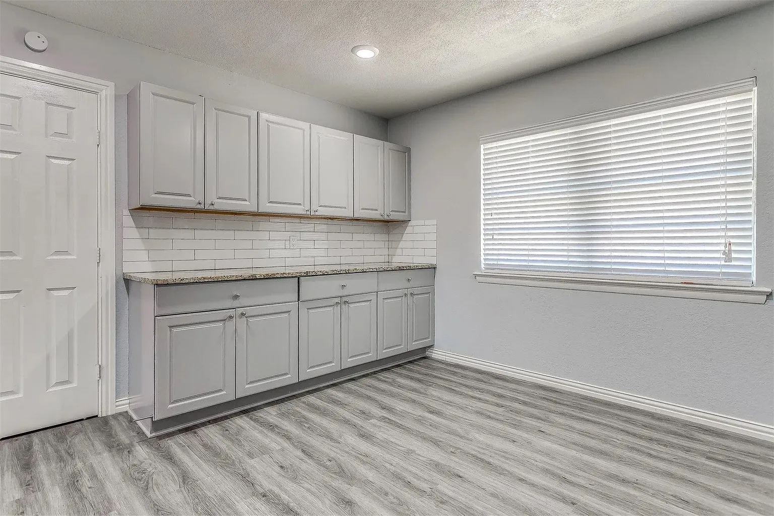 Light gray cabinetry with a subway tile backsplash, light-toned countertop, wood-finish flooring, and recessed​​‌​​​​‌​​‌‌​‌‌​​​‌‌​‌​‌​‌​​​‌​​ lighting