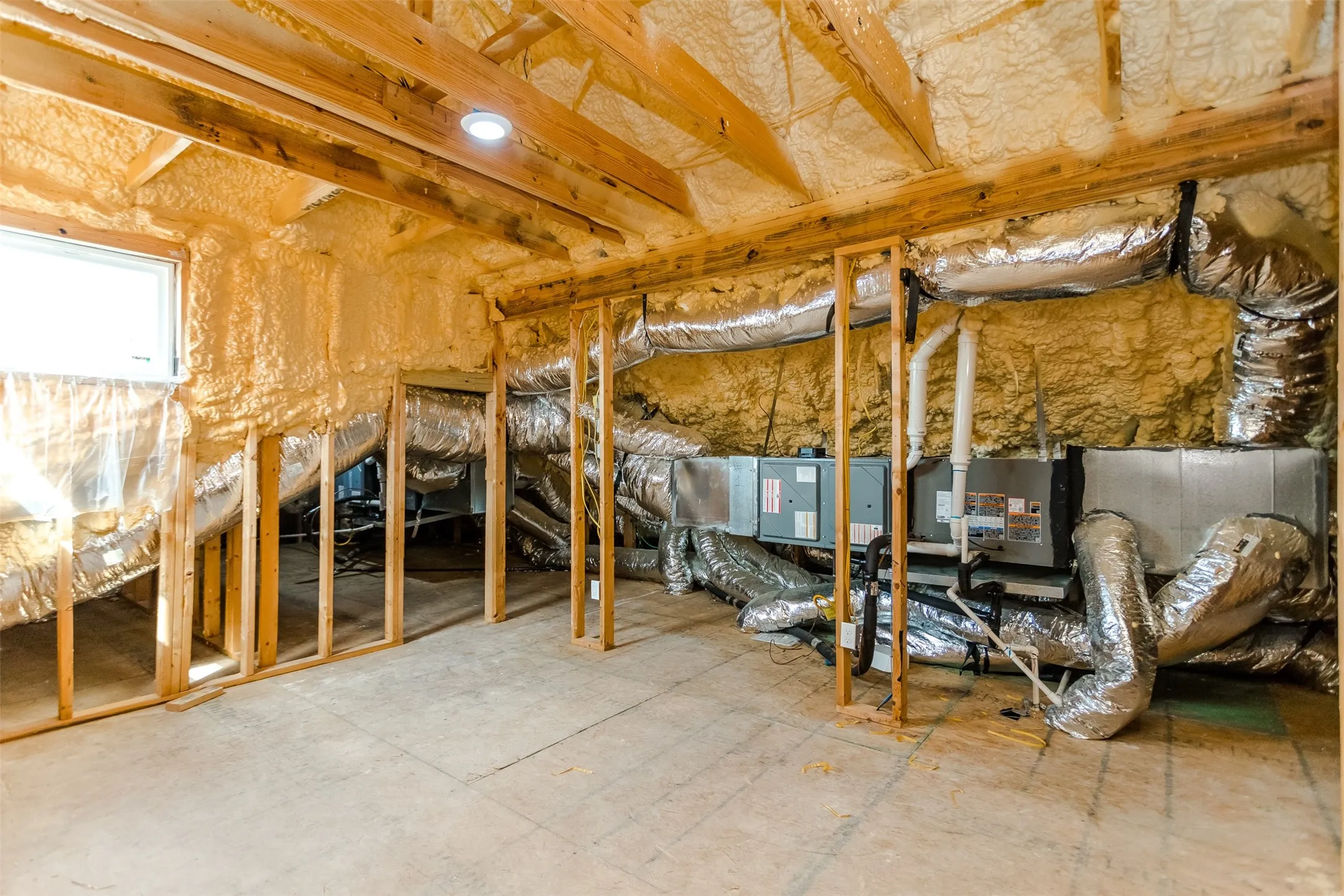 Exposed wood framing, spray foam insulation, window, recessed lighting, and visible HVAC ductwork