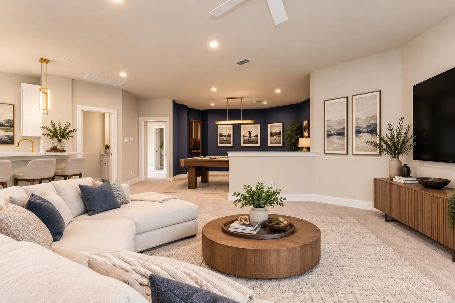 Recessed lighting and a ceiling fan illuminate a spacious open-concept room with light-toned carpeting