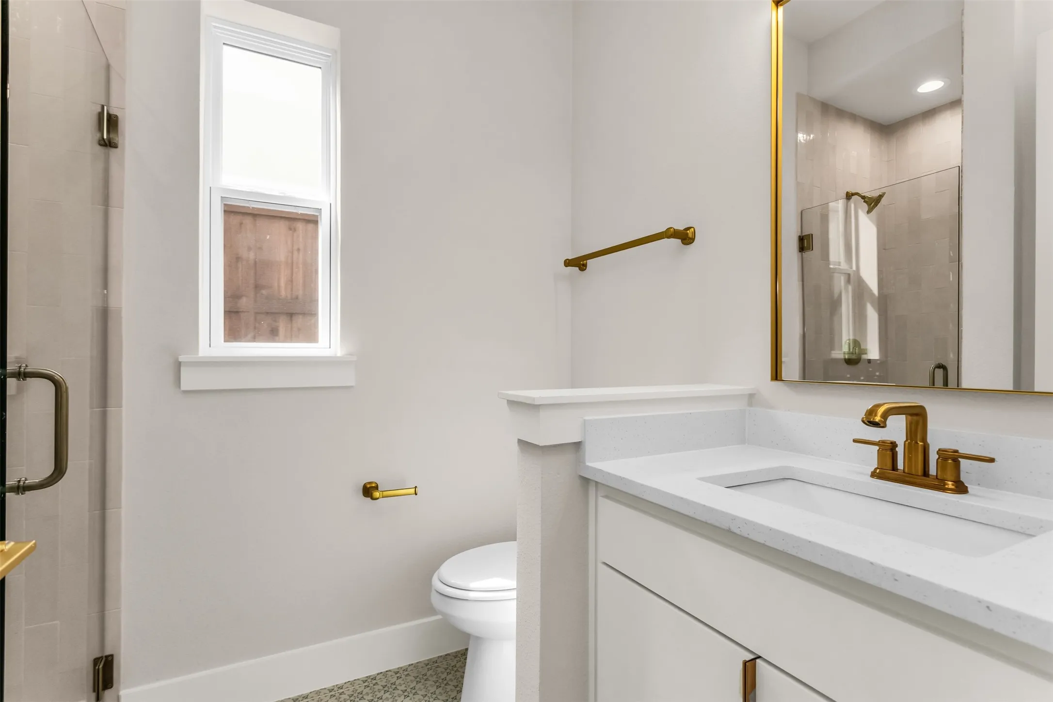 Built-in vanity with a single basin sink, gold-finish faucet, and coordinating gold-frame mirror