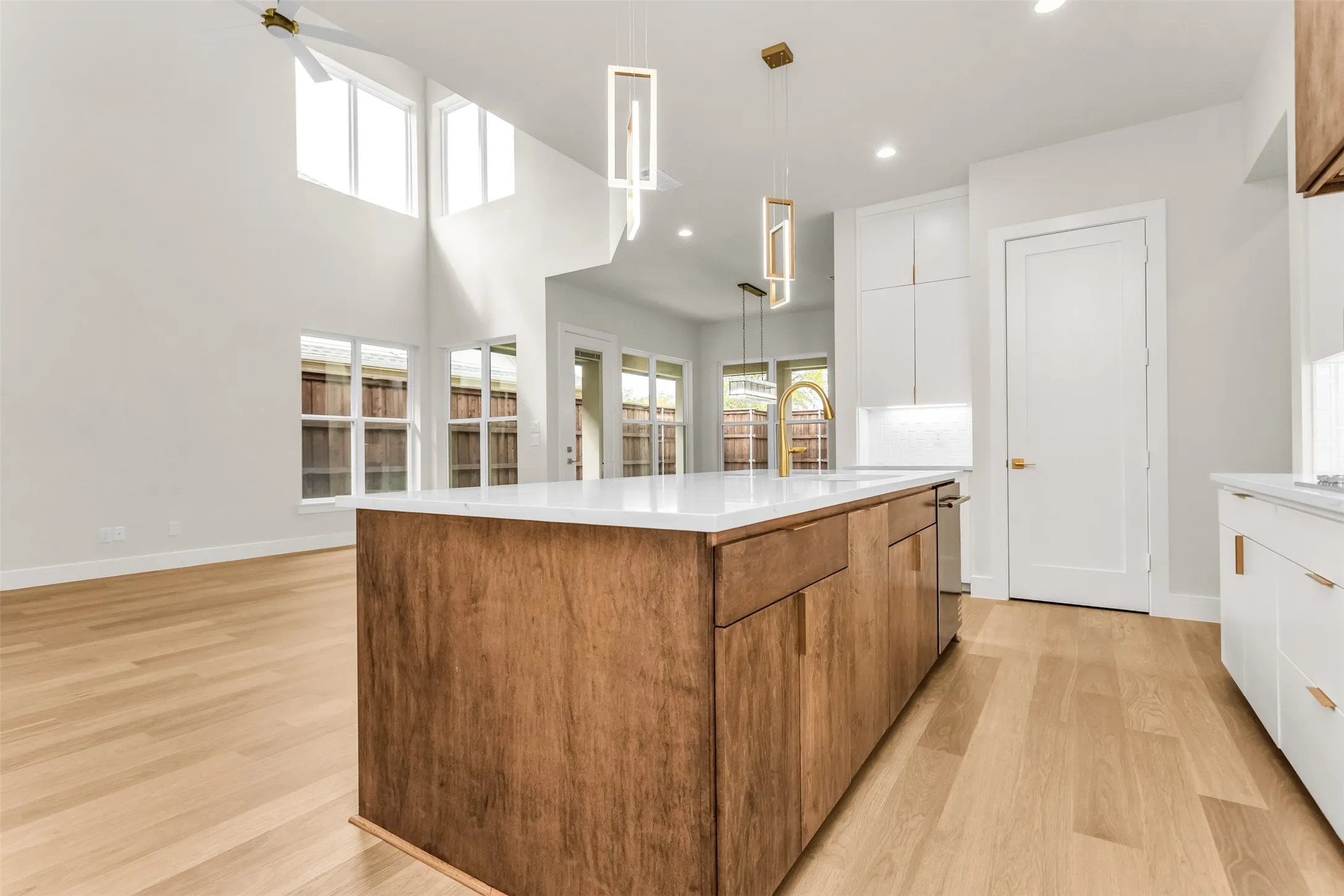 Open-concept kitchen featuring a wood-finish island with a white countertop, recessed lighting, and light wood-finish flooring