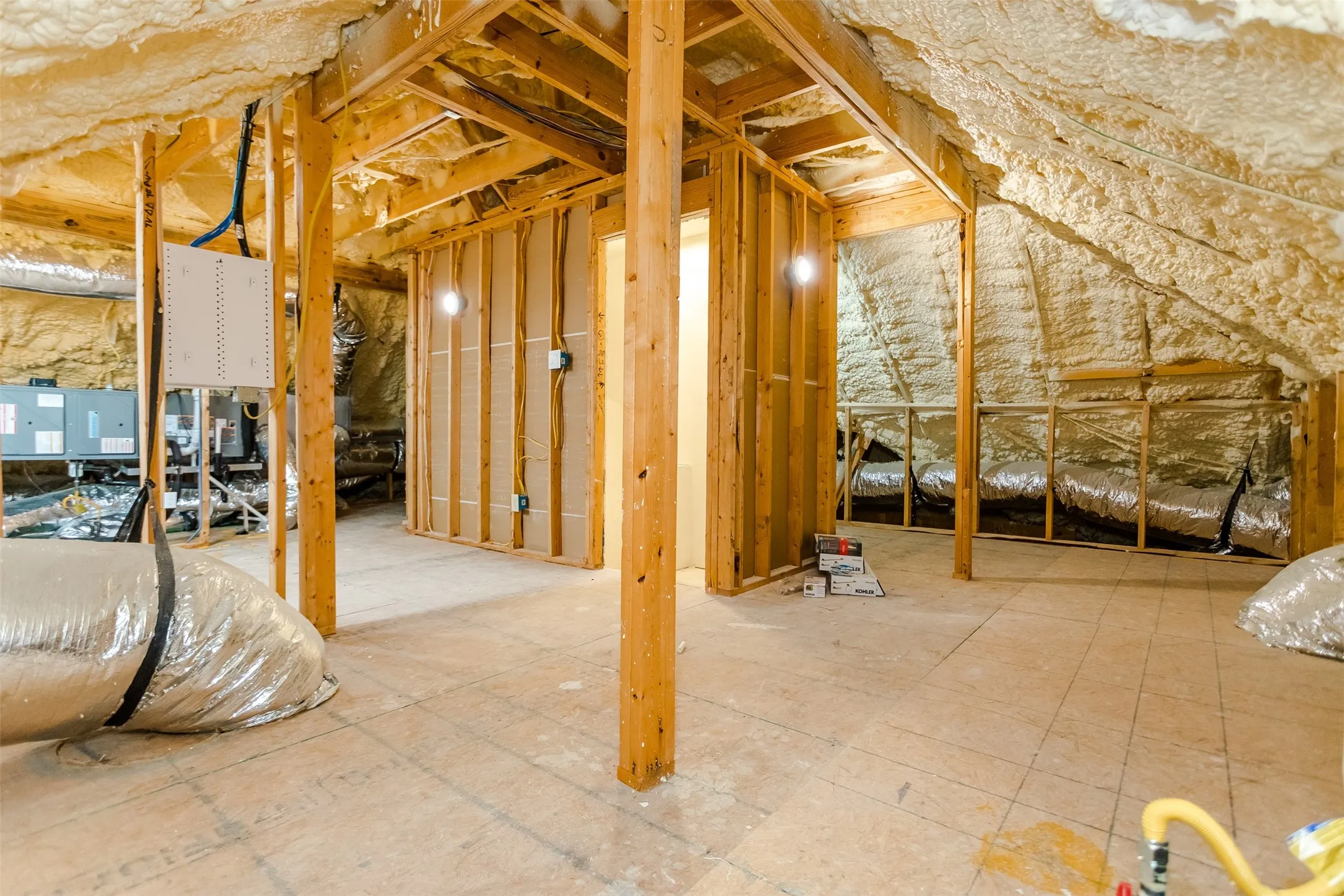 Unfinished attic space with exposed wood framing, spray foam insulation, and visible HVAC ductwork