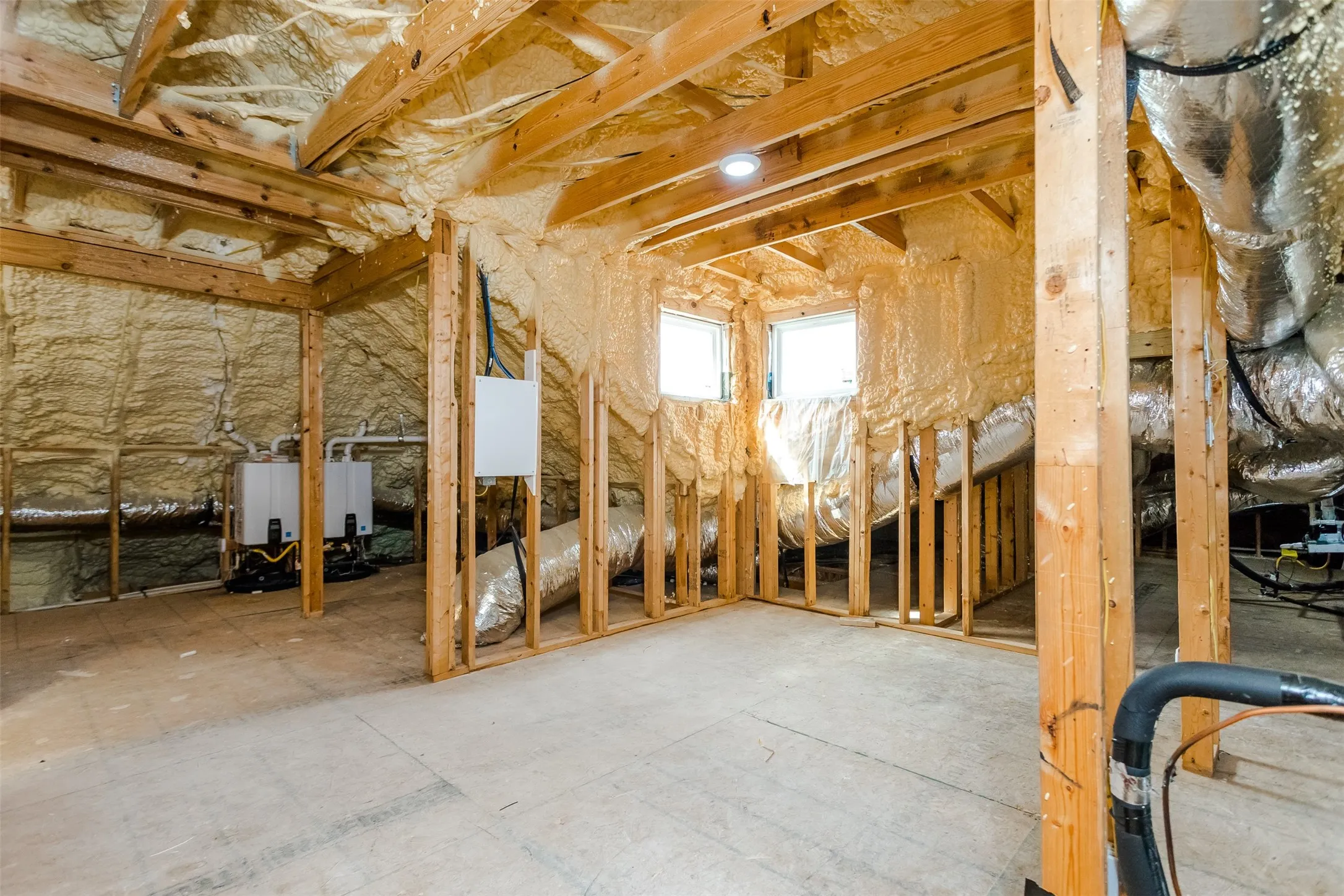 Exposed wood framing with spray foam insulation, two windows, and built-in mechanical equipment