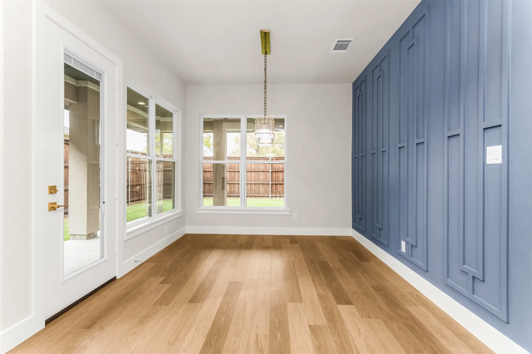 Wood-finish flooring, a decorative accent wall, recessed lighting, and multiple windows with clear glass panels