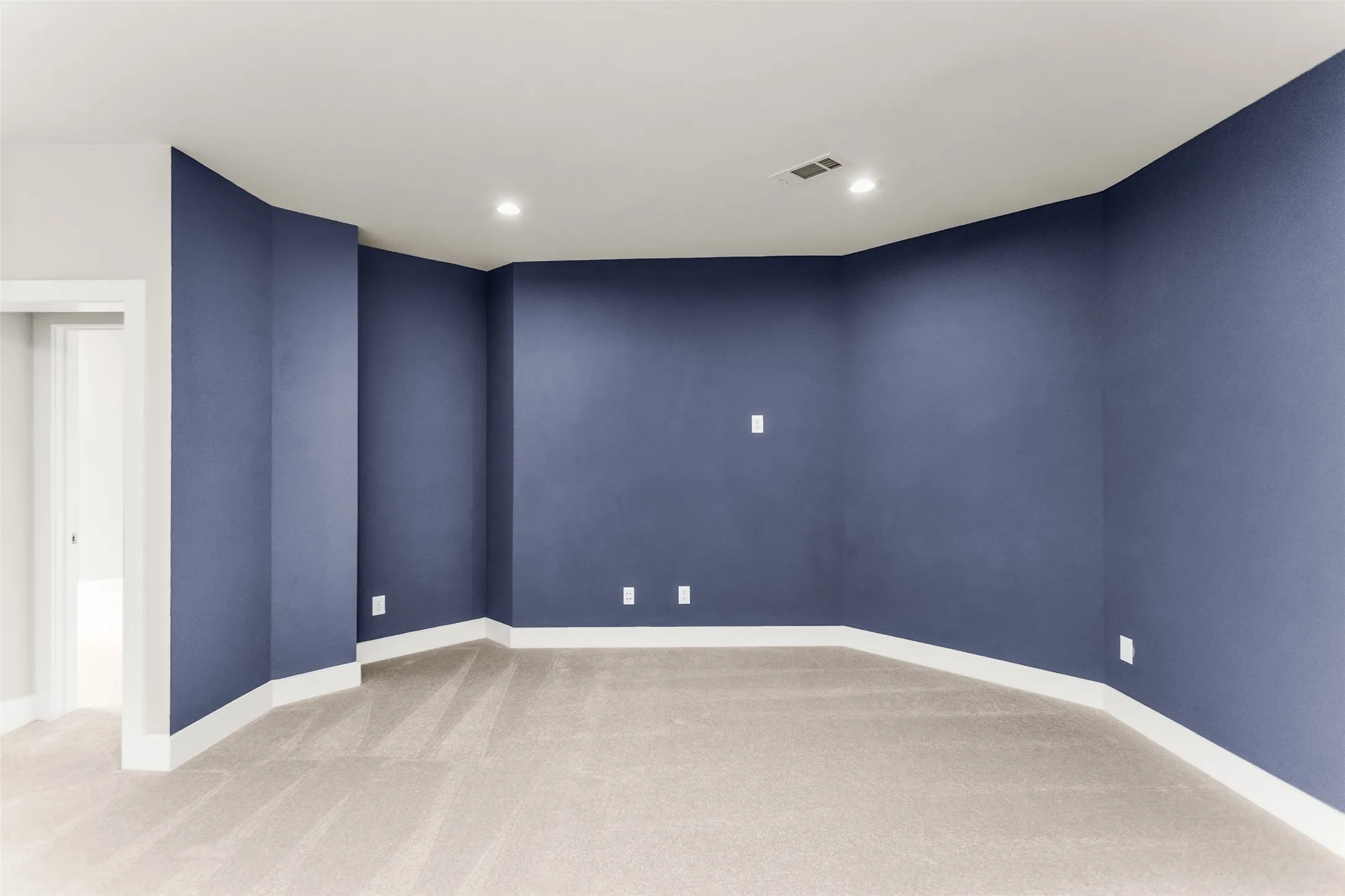 Recessed ceiling lighting, light-toned carpeting, white trim, and a doorway with white casing
