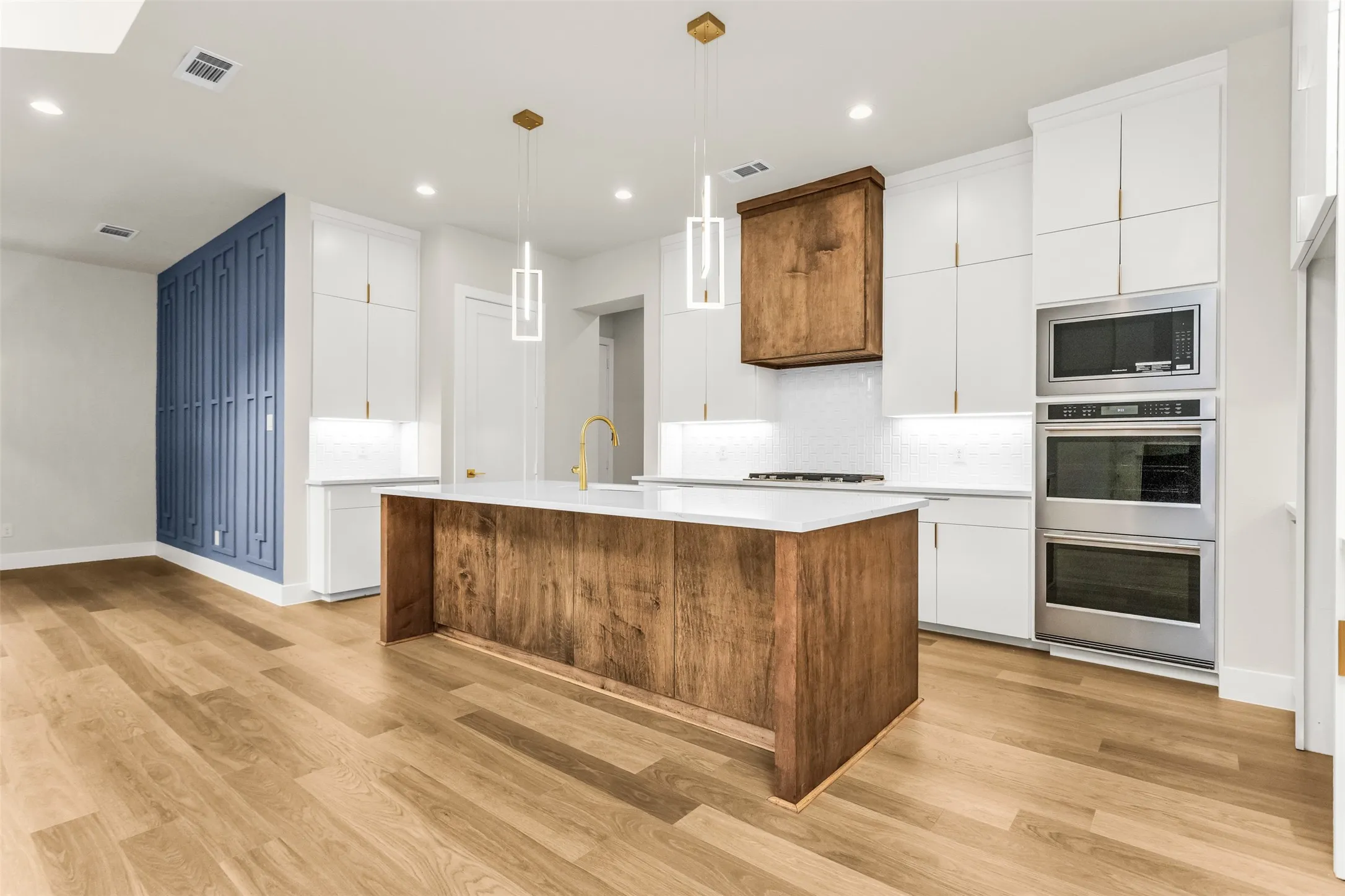 Kitchen featuring a wood-finish island with a white countertop, white cabinetry, stainless steel double ovens, and wood-finish flooring
