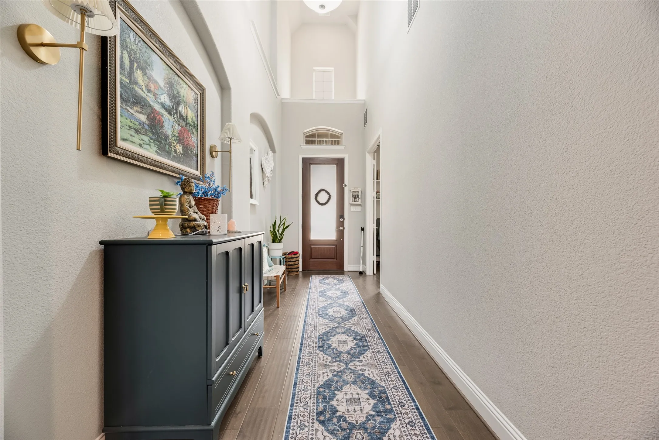 Entryway featuring wood-finish flooring, high ceilings, a transom window, and an arched doorway