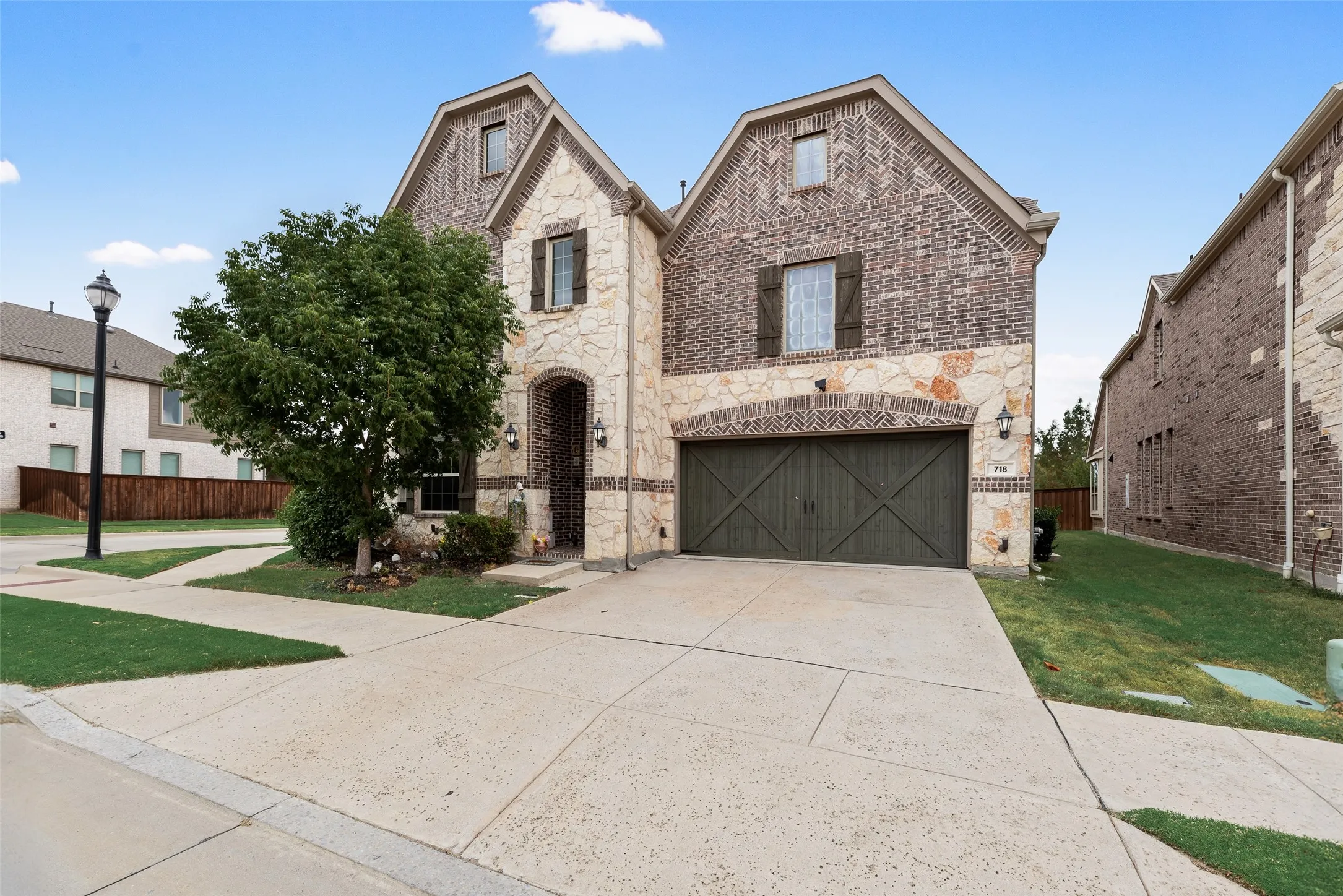 Stone and brick exterior with wood shutters, arched entry, and an attached garage with a wood-finish door