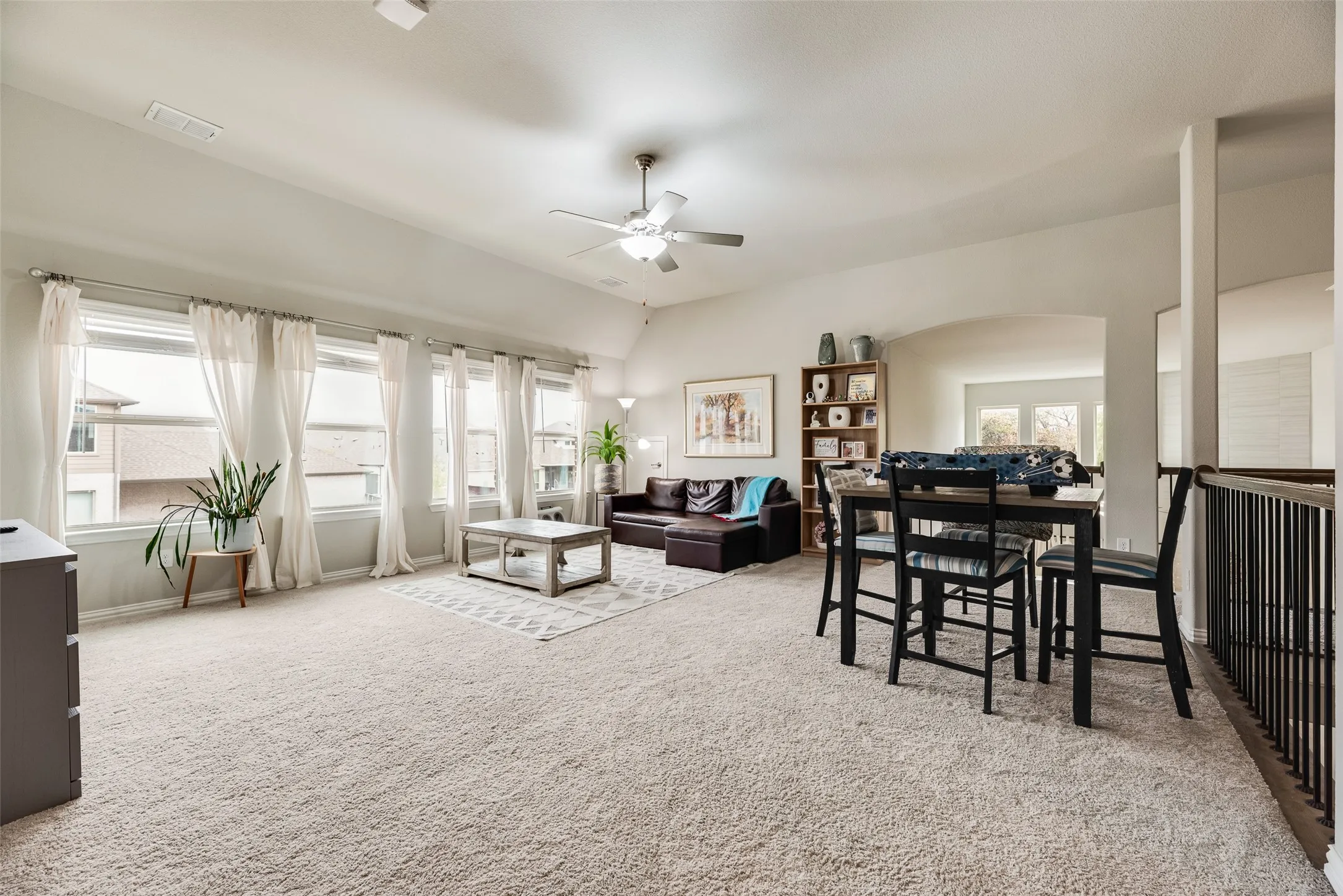 Vaulted ceiling, multiple windows with white trim, recessed lighting, ceiling fan, and arched entryway