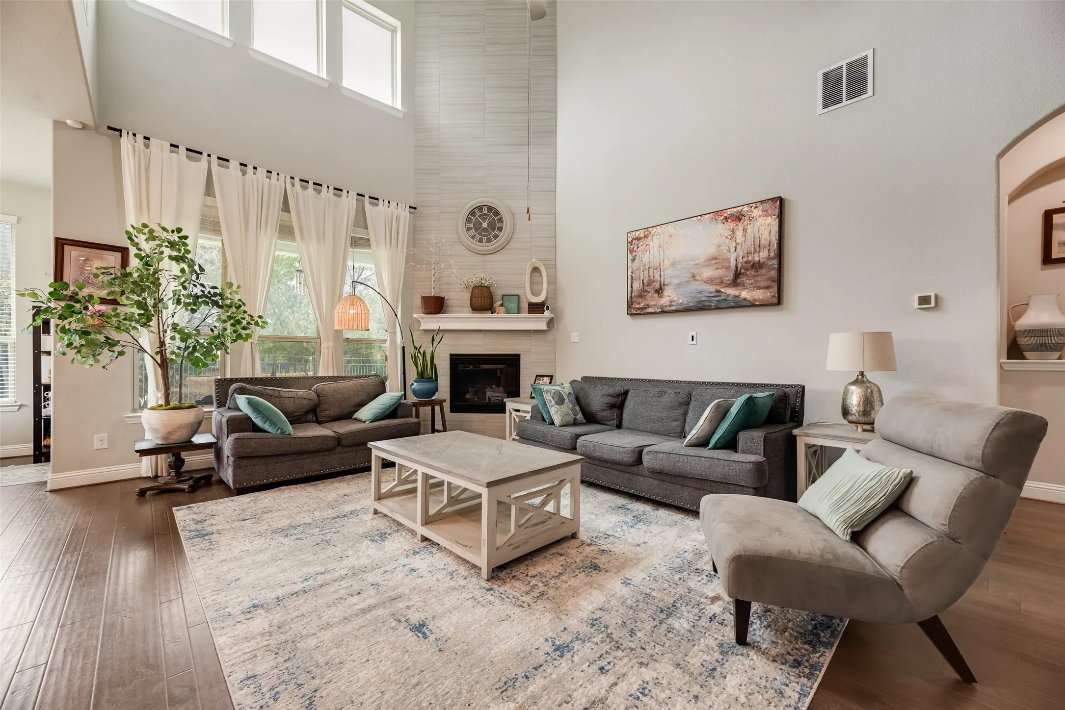 Vaulted ceiling, wood-finish flooring, fireplace with white mantel, upper transom windows, and arched doorway