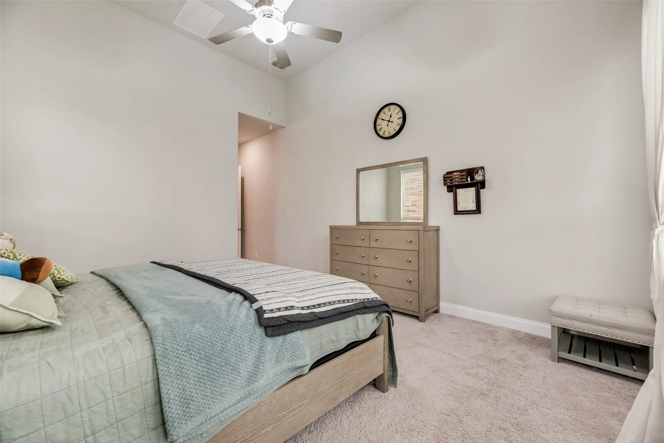 Vaulted ceiling with a ceiling fan, light-colored carpet, and a neutral wall palette