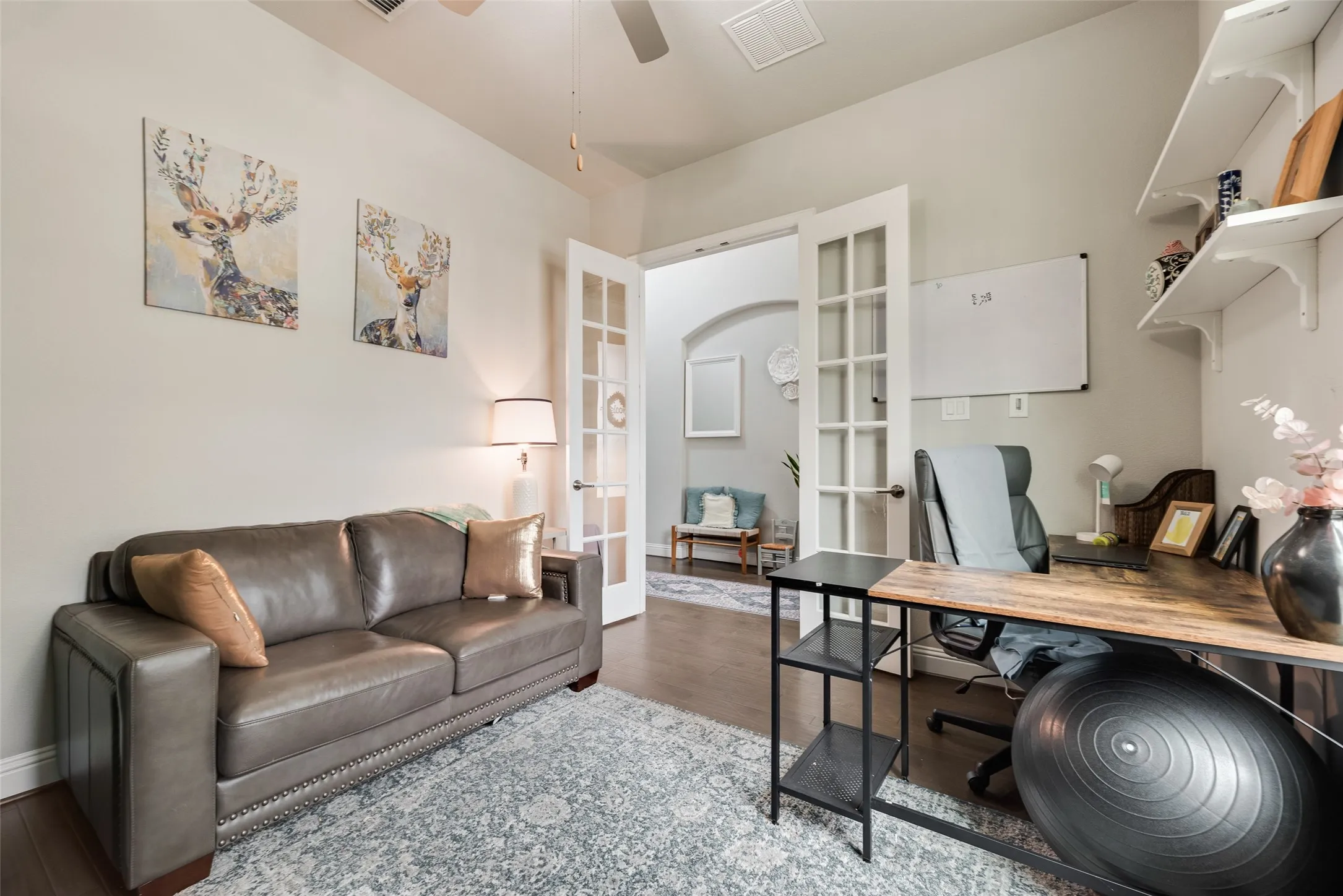 French doors with glass paneling, overhead ceiling fan, wood-finish flooring, built-in wall shelving, and an arched entry