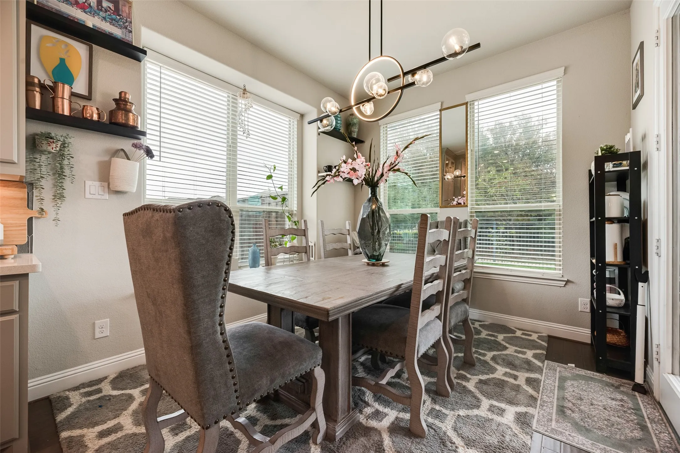 Dining area featuring a contemporary chandelier, multiple windows with blinds, built-in shelving, and wood-finish flooring
