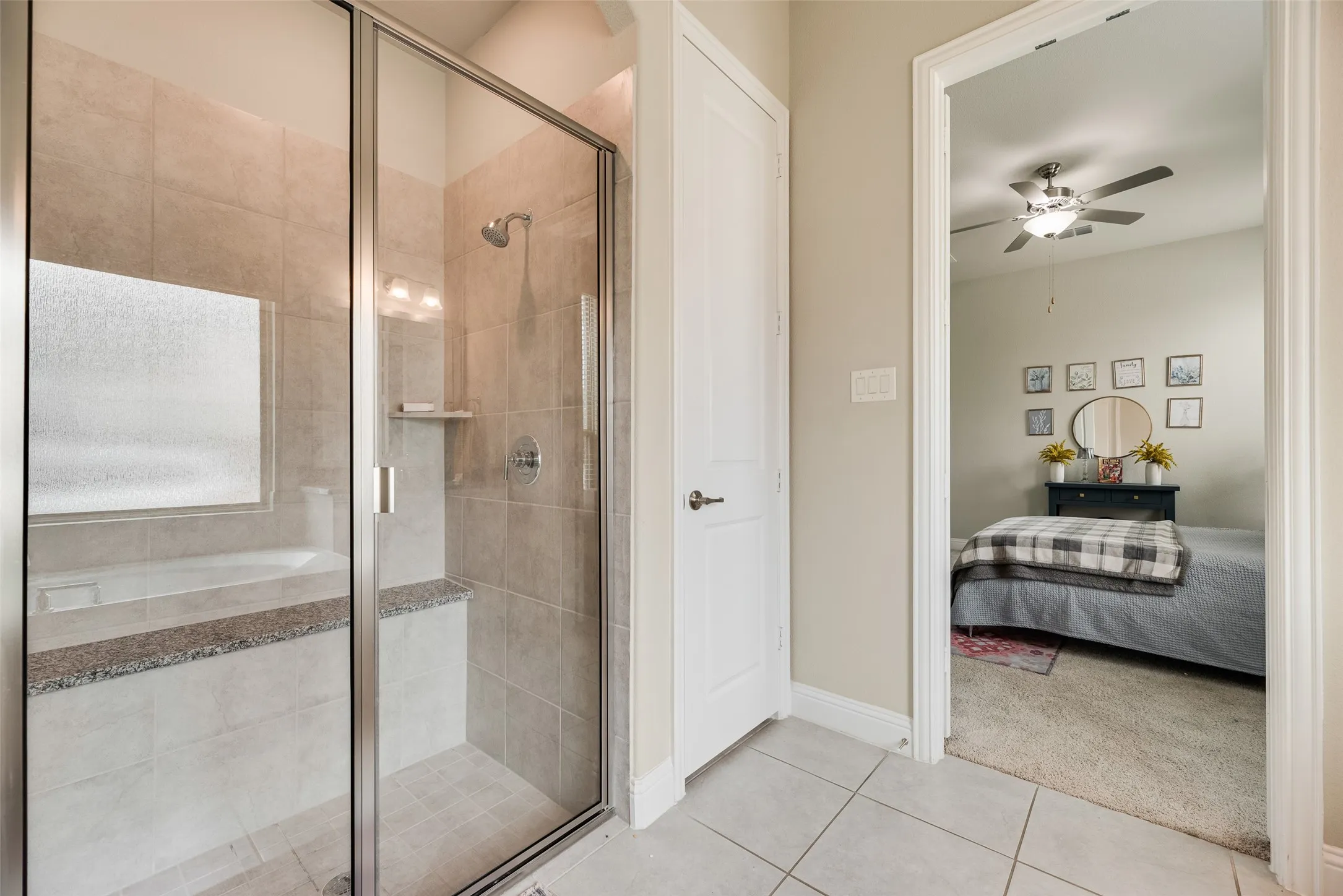 Glass-enclosed shower with a built-in bench, tiled walls, and a separate soaking tub