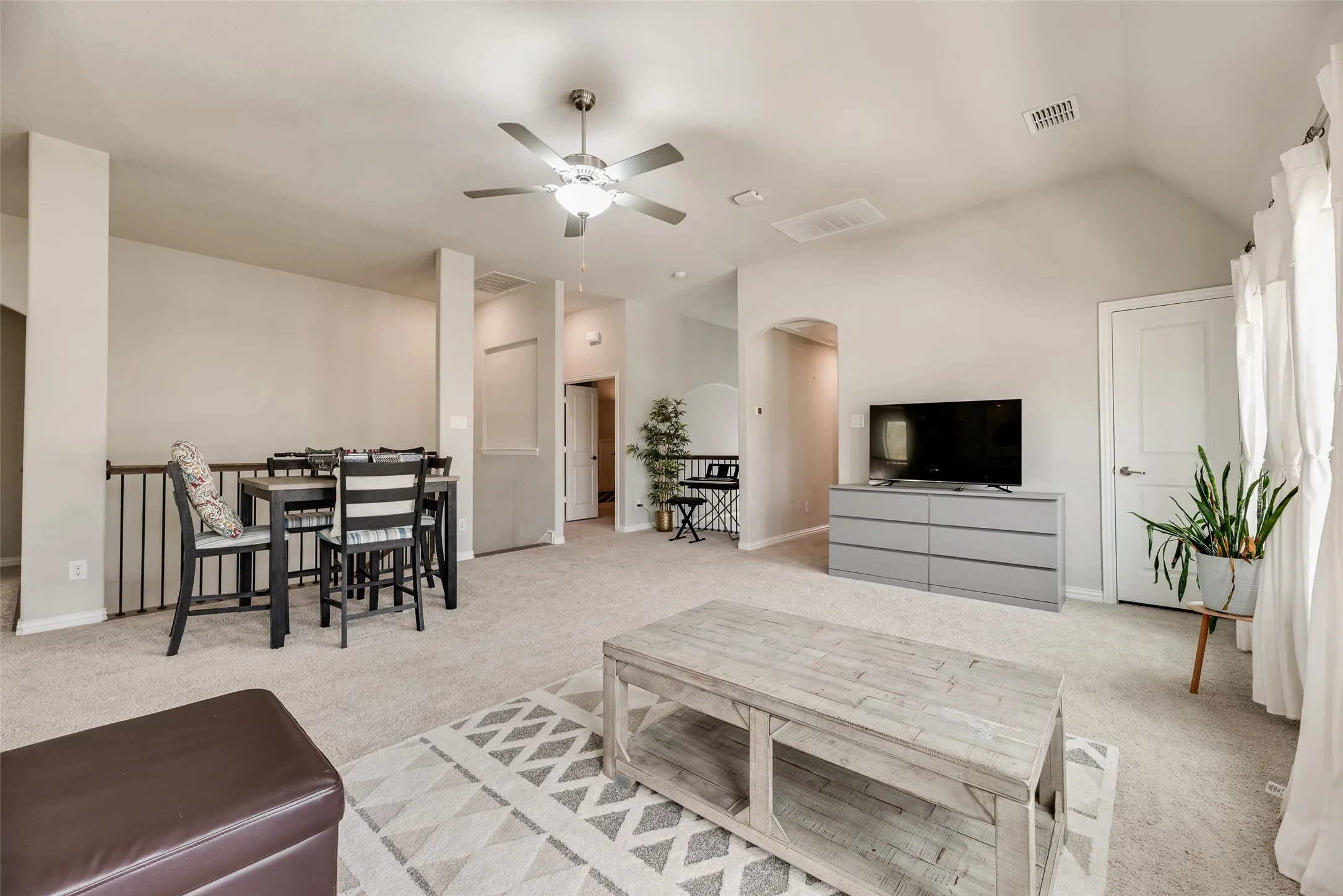 Carpeted flooring, vaulted ceiling, ceiling fan with integrated lighting, and white interior doors with brushed nickel hardware