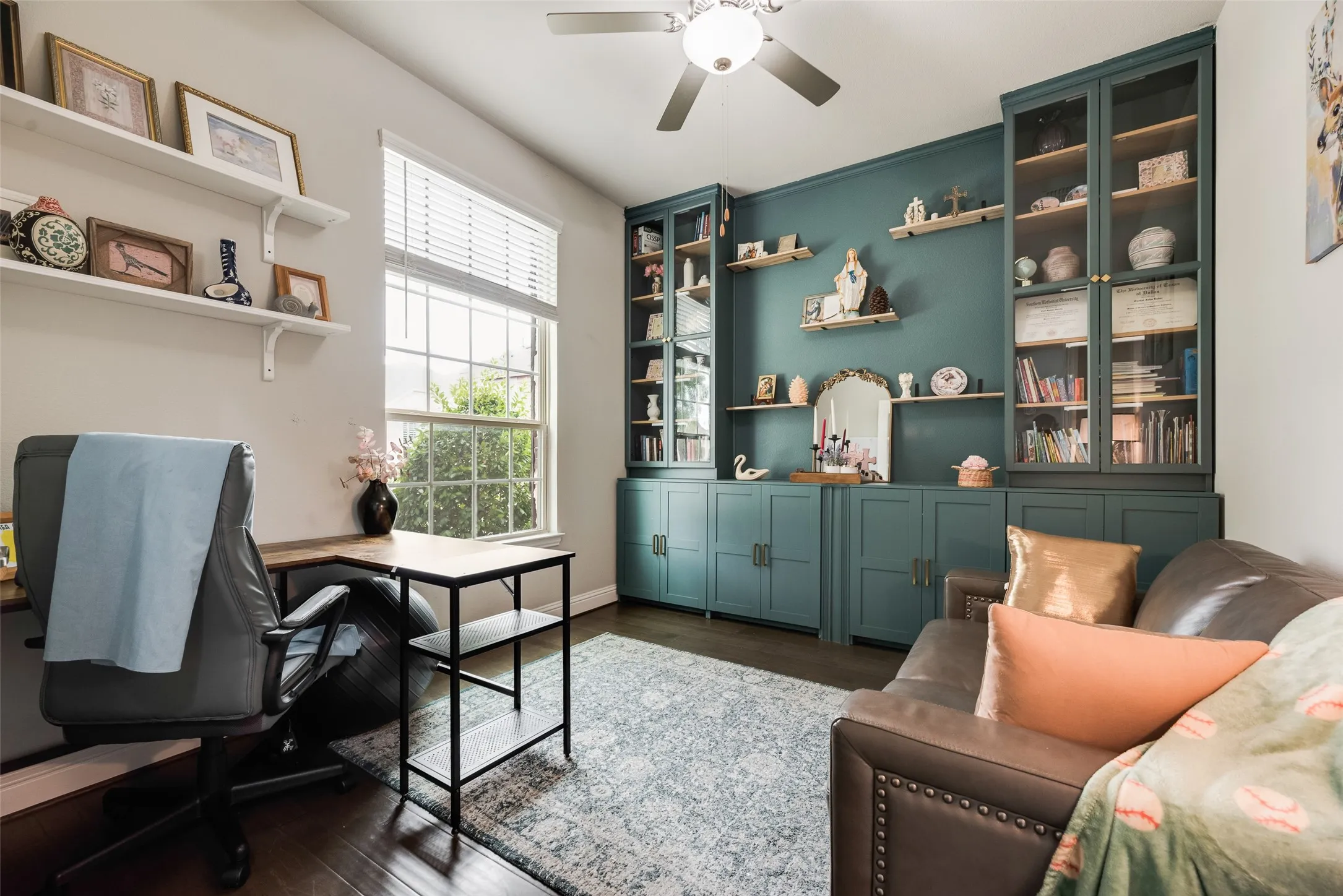 Vaulted ceiling with a ceiling fan, a window with blinds, dark wood-finish flooring, and built-in cabinetry with glass-front uppers