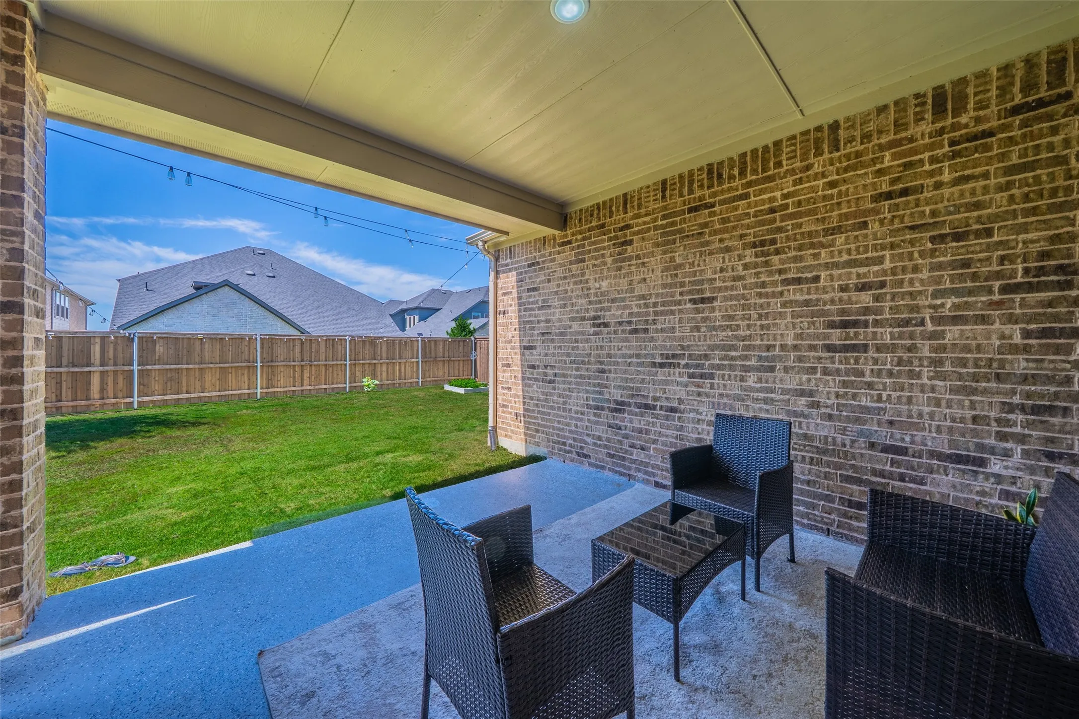 Covered patio with brick wall and concrete flooring