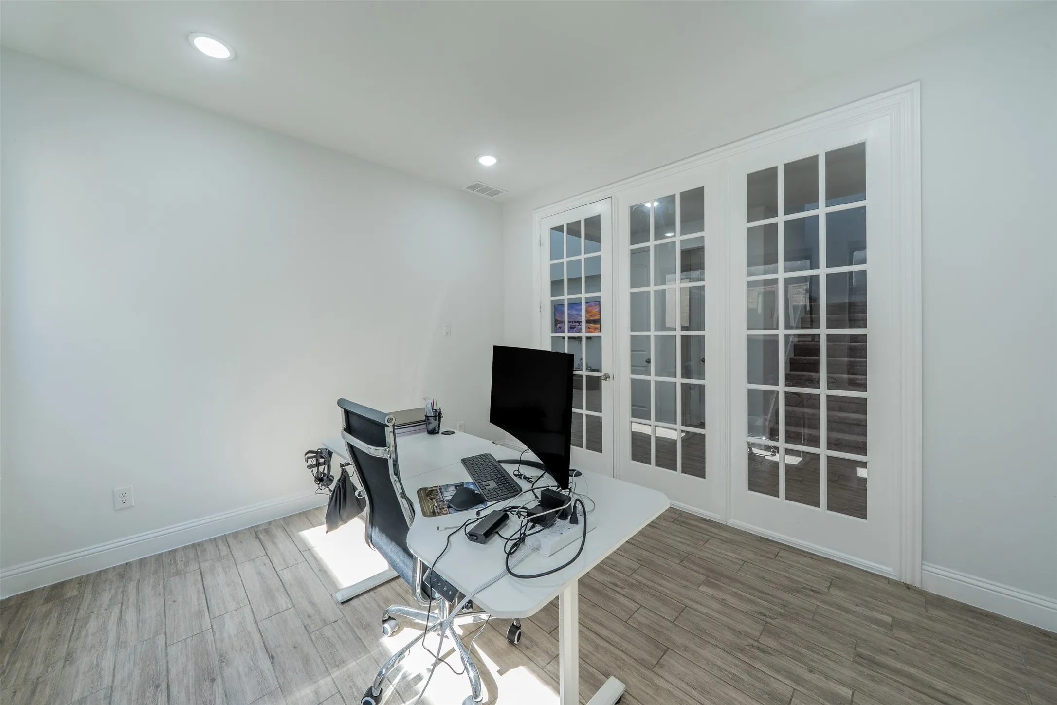 Wood-finish flooring, recessed lighting, and white walls