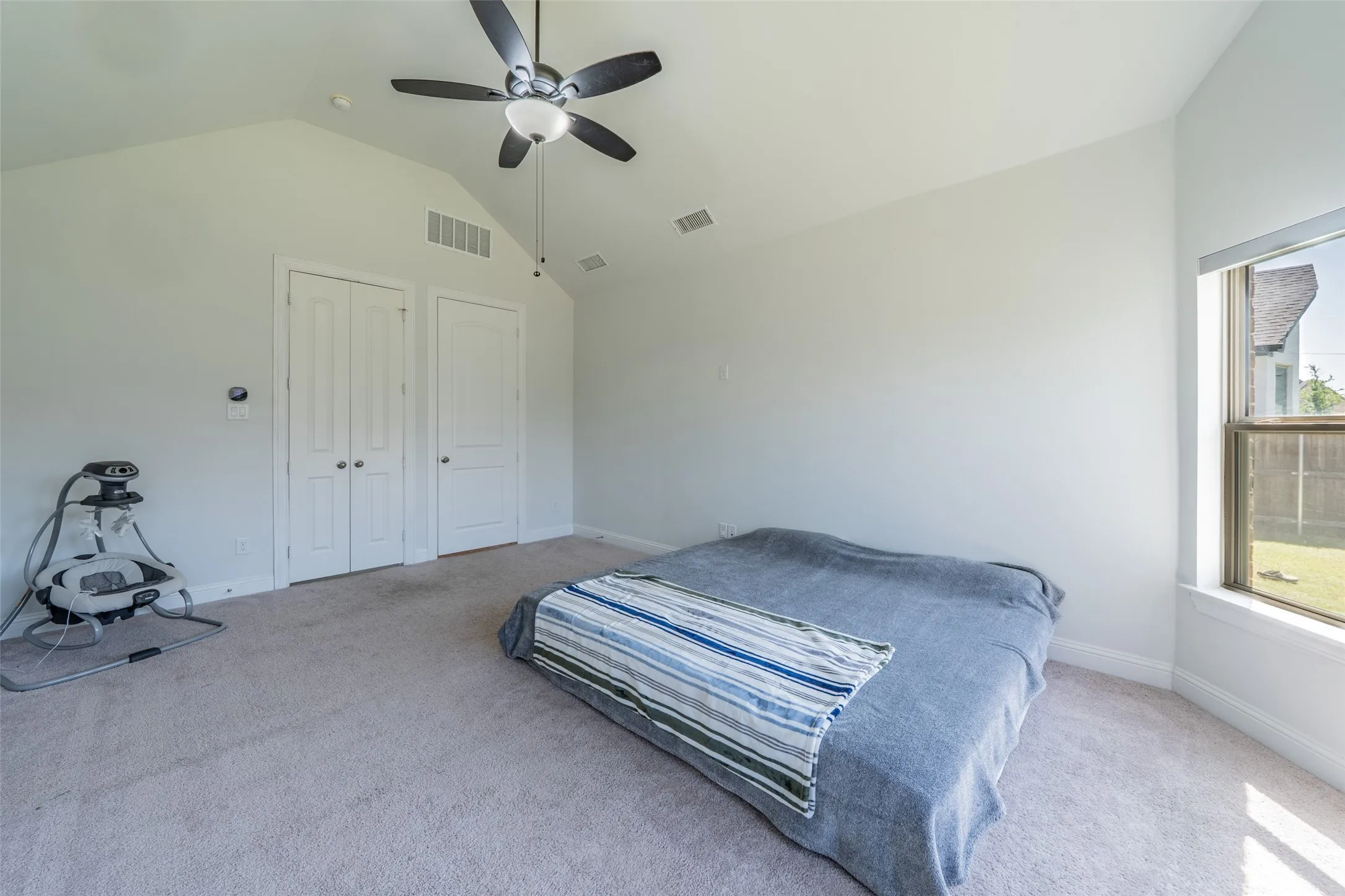 Vaulted ceiling with a ceiling fan, carpeted flooring, and a large window
