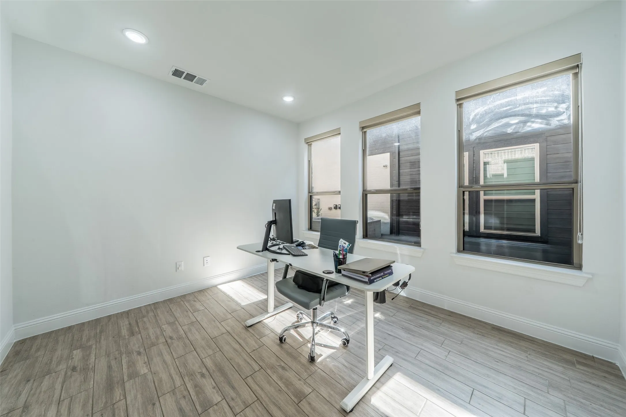Recessed lighting, light wood-finish flooring, multiple windows, white wall finishes, and white trim