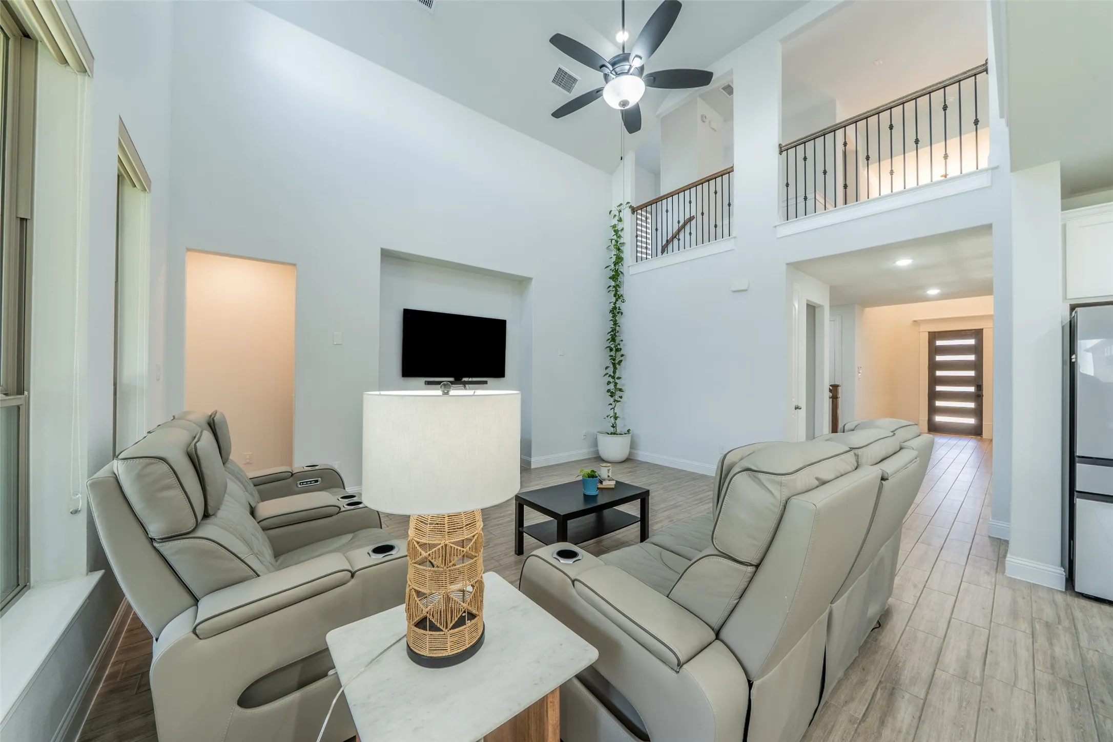 Vaulted ceiling living area featuring wood-finish flooring, a contemporary ceiling fan, and an integrated media niche