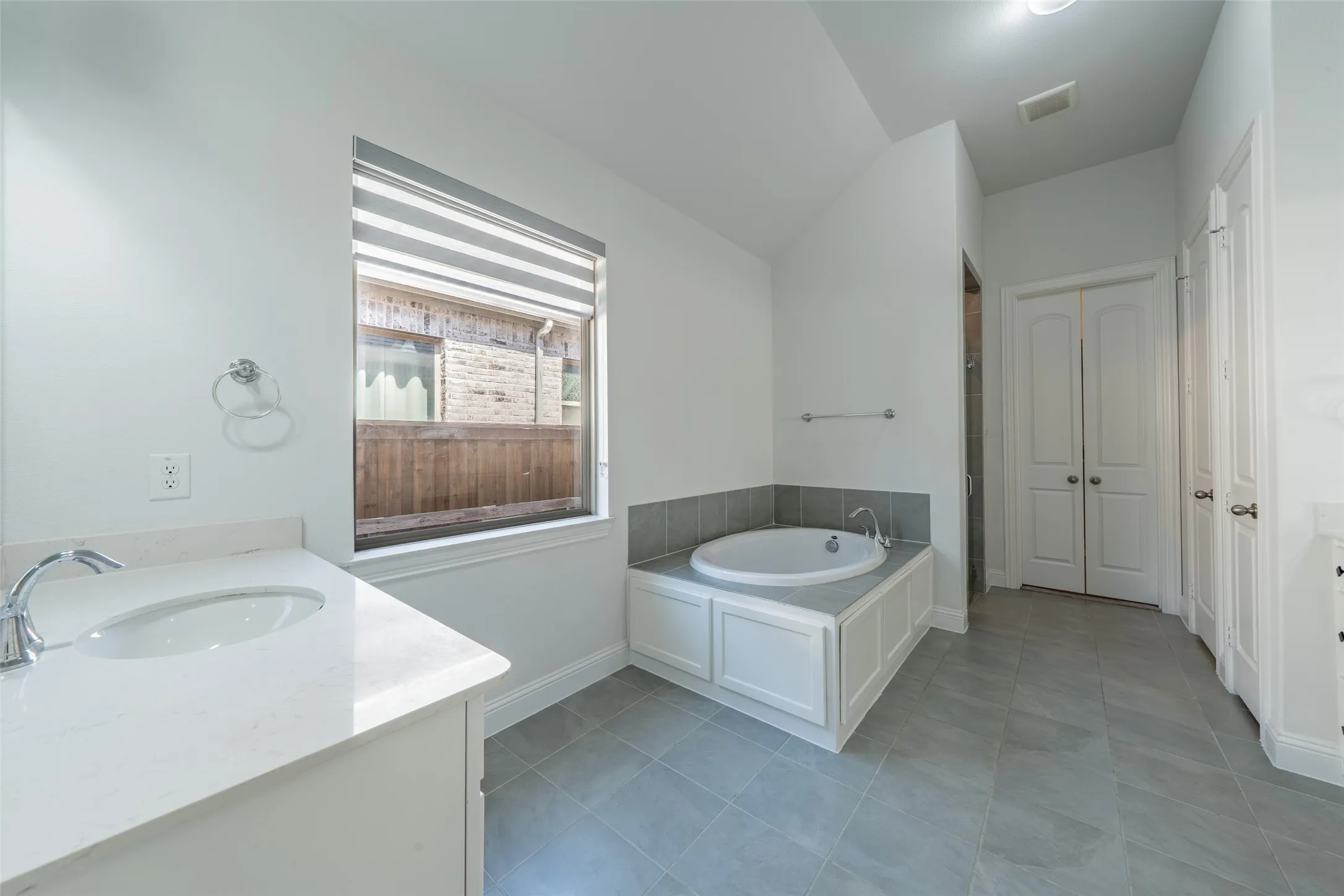 Spacious bathroom with a built-in tub, dual vanity, and tiled flooring