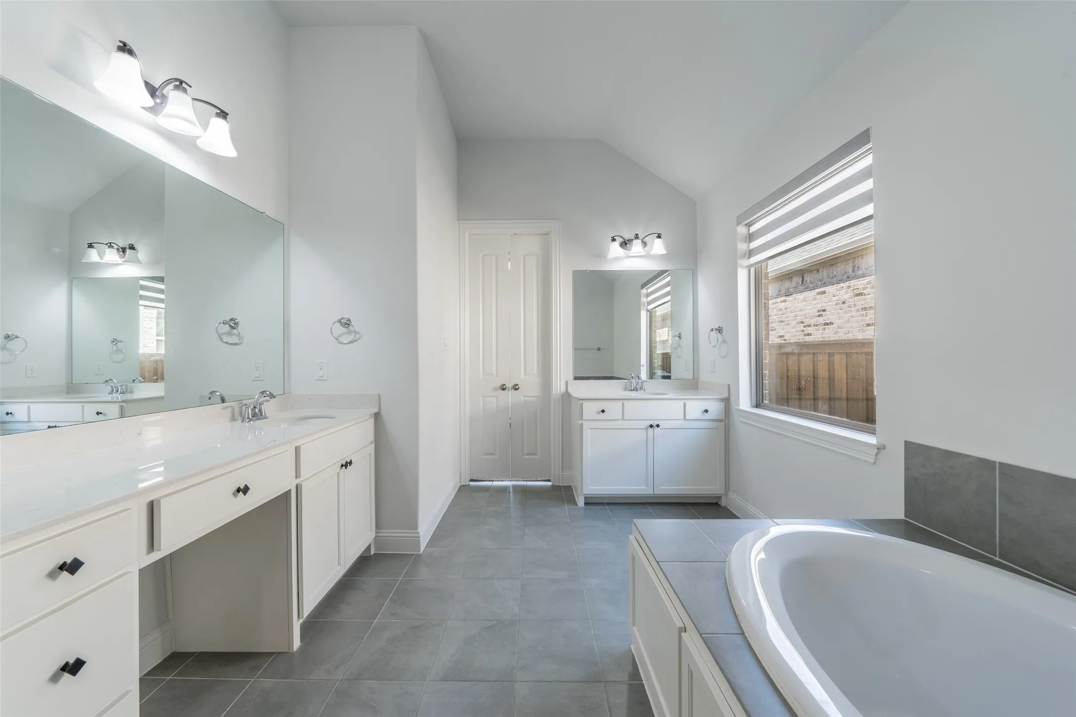Dual vanity with integrated sinks, white cabinetry, and a built-in makeup area