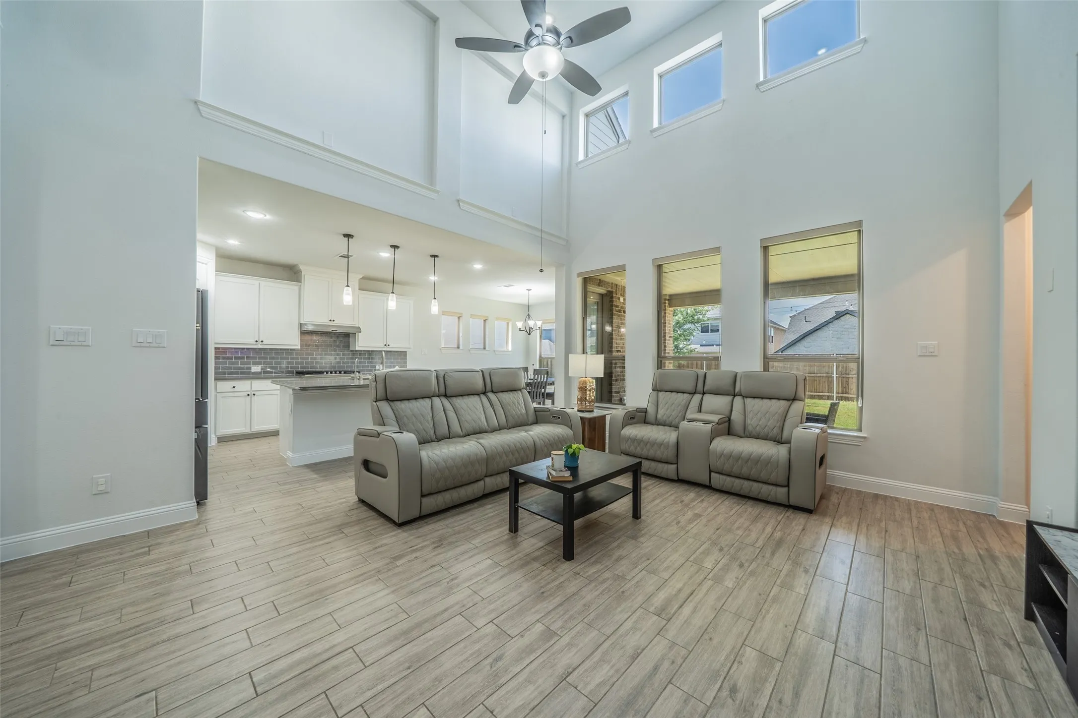 Two-story living area featuring a ceiling fan, multiple windows, and wood-finish flooring