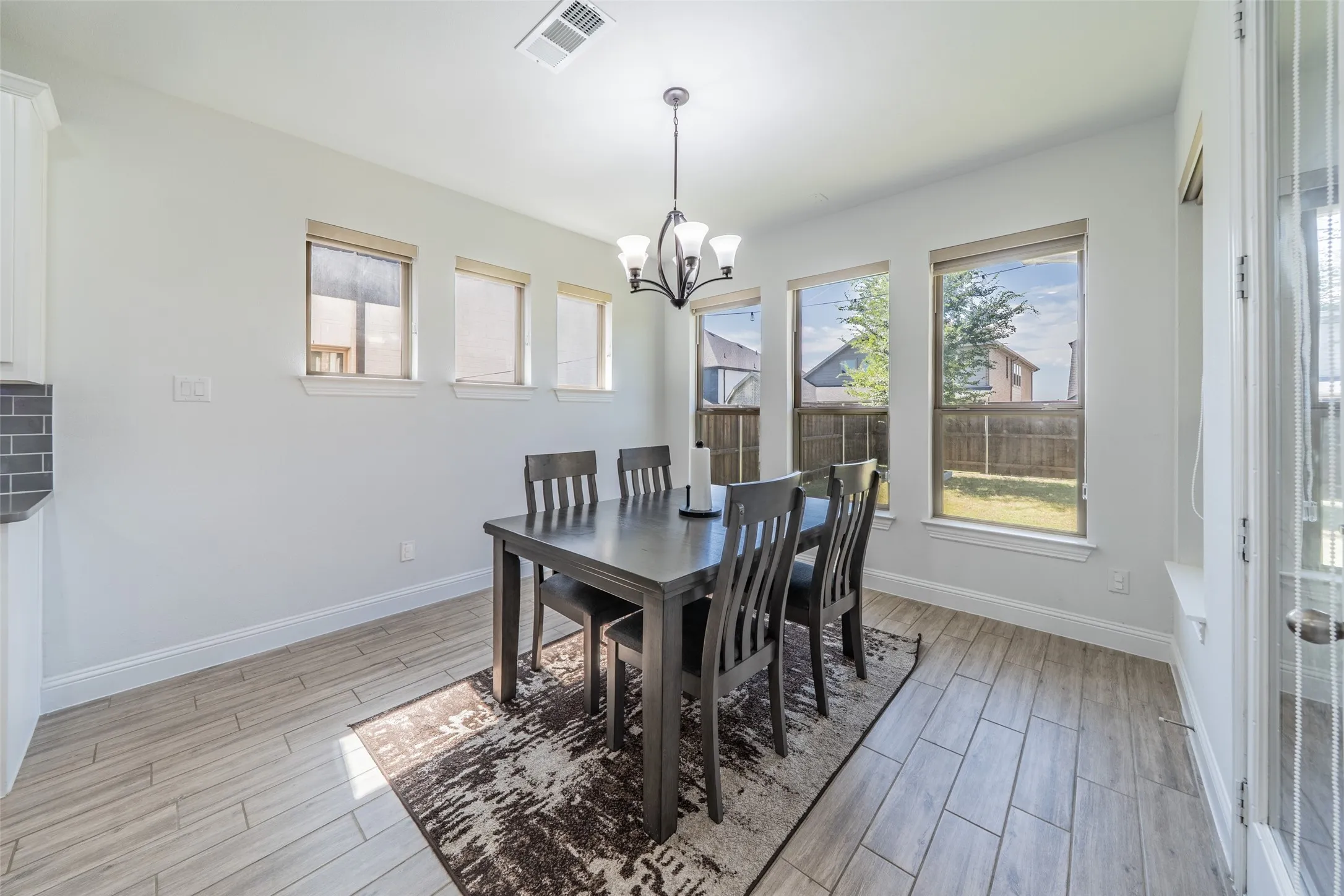 Expansive room featuring light wood-finish flooring, multiple windows, and a chandelier