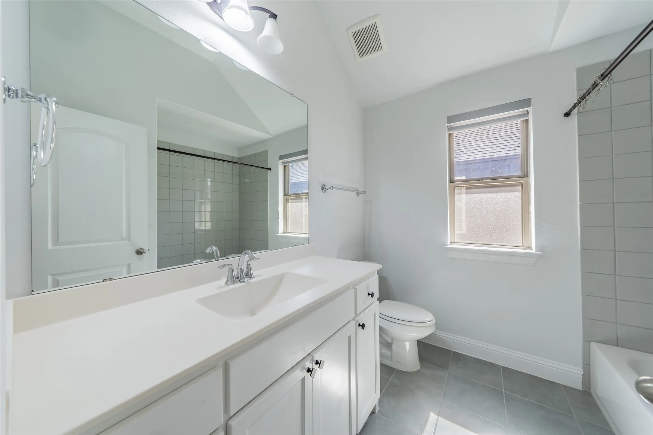 White vanity with integrated sink, chrome-finish faucet, and large rectangular mirror