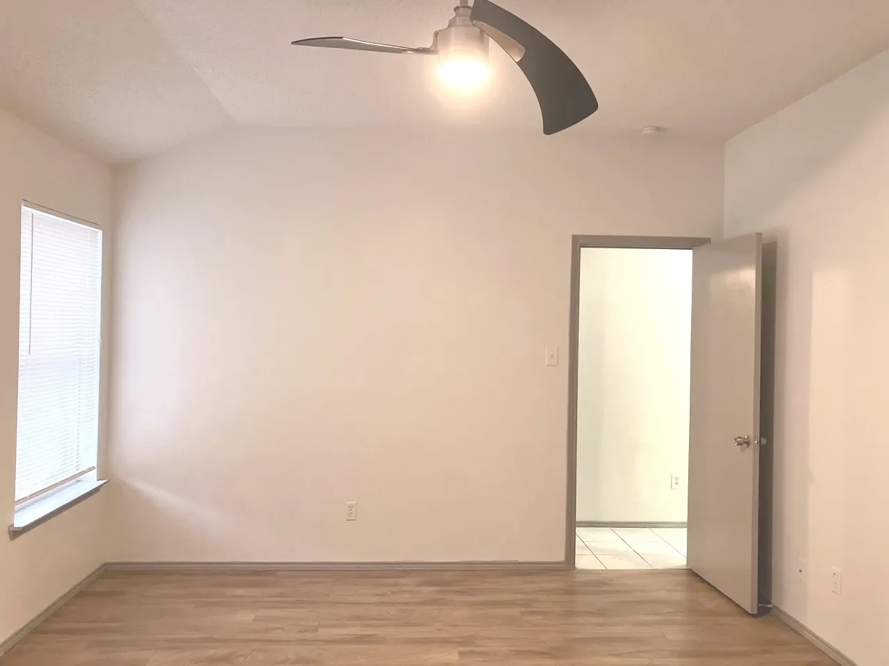 Vaulted ceiling with a ceiling fan, wood-finish flooring, and a single window with blinds