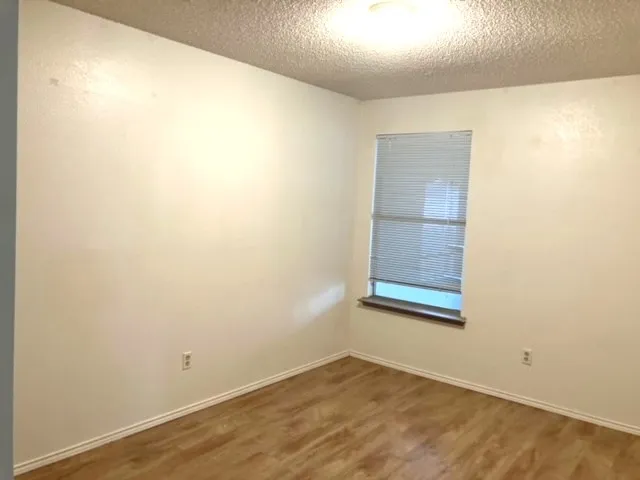 Wood-finish flooring, neutral wall tones, and a window with blinds provide a clean interior