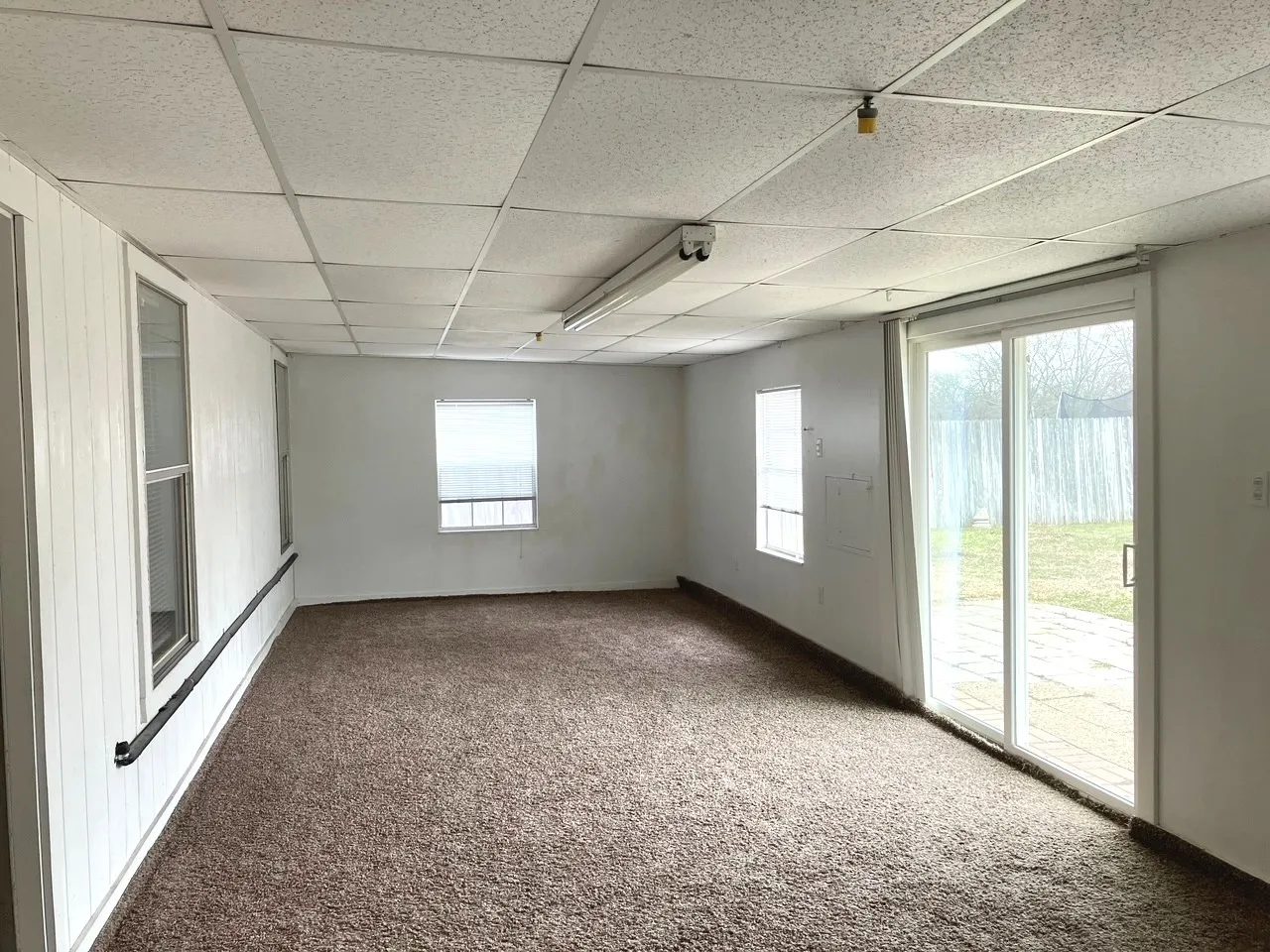 Expansive room with neutral carpet flooring and multiple windows for natural light