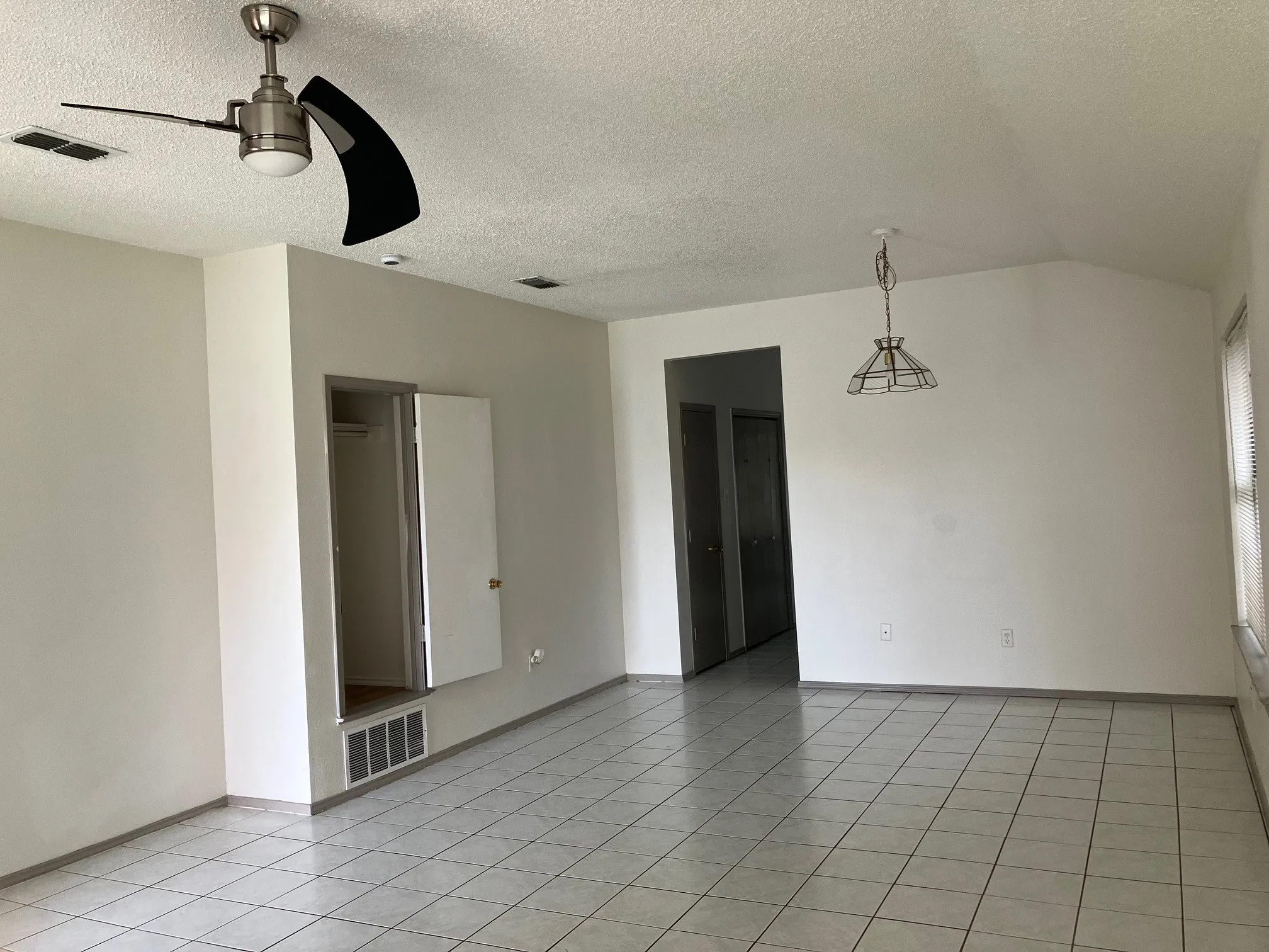 Angled ceiling, tiled flooring, ceiling fan with integrated lighting, recessed lighting, and a suspended light fixture