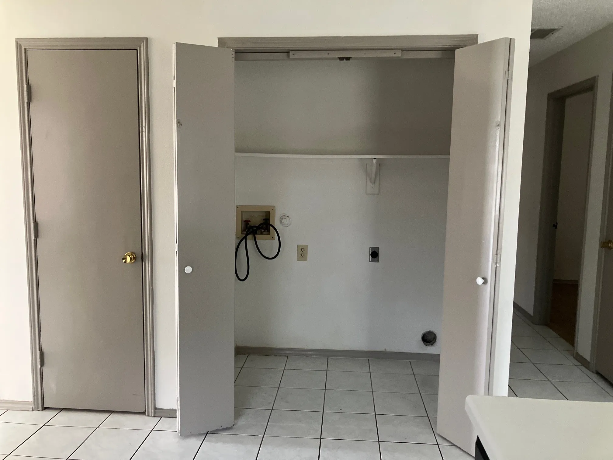 Utility closet with bi-fold doors, tile flooring, and integrated shelving