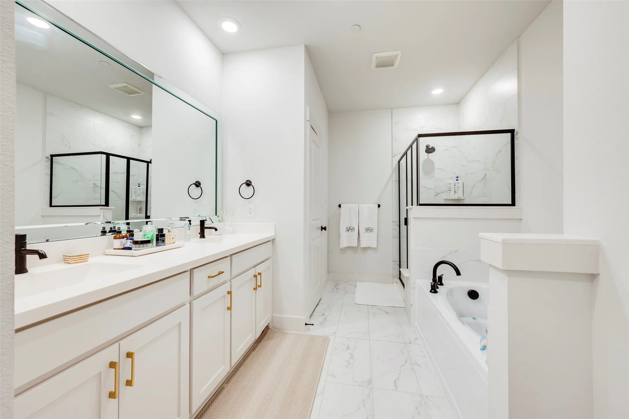 Dual vanity with stone-finish countertops, white cabinetry, and gold-tone hardware