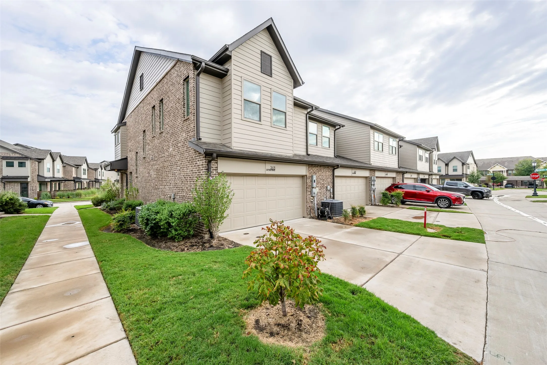 Multi-story townhome featuring brick and siding exterior, an attached garage, and a concrete driveway