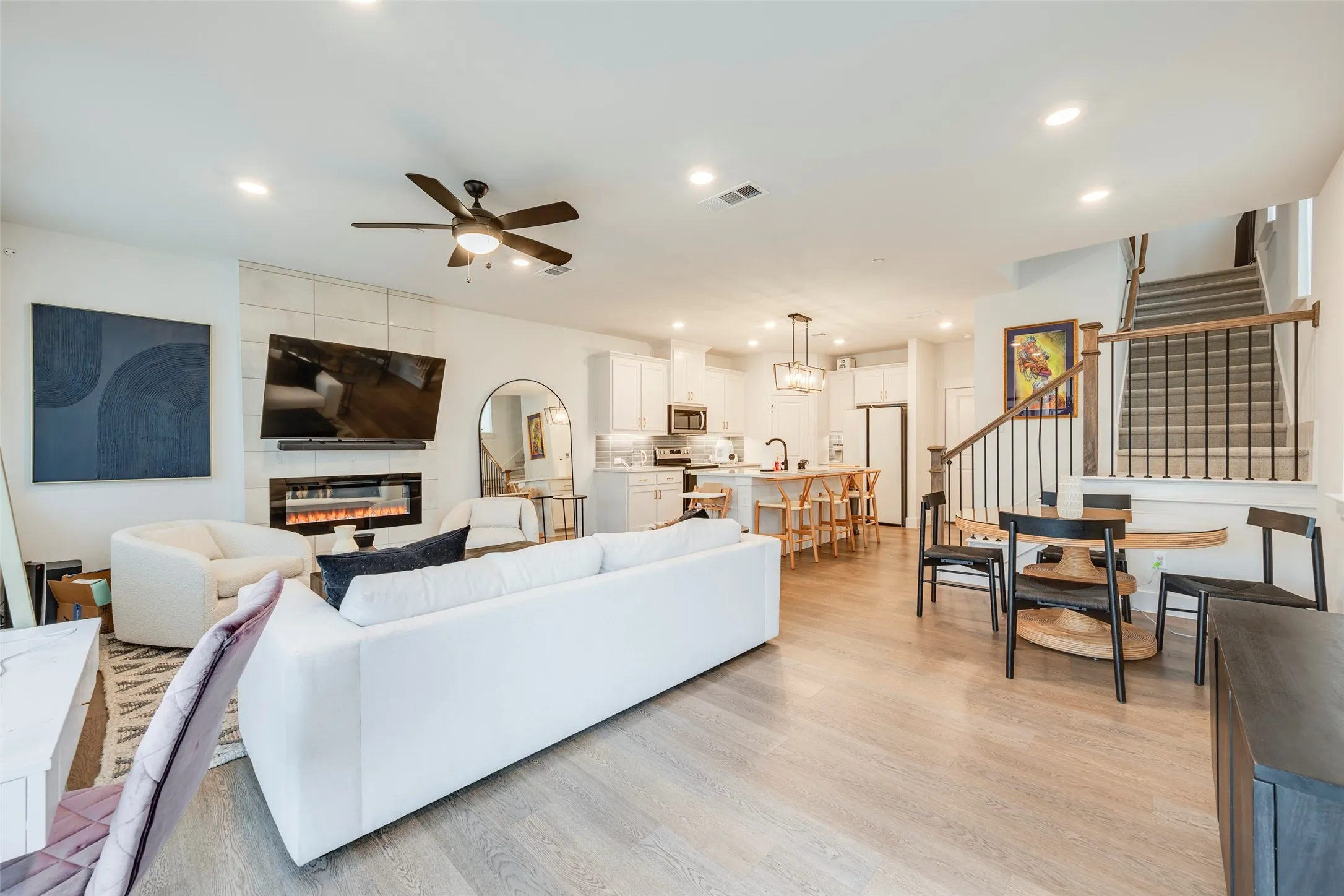 Open-concept living space featuring wood-finish flooring, a contemporary fireplace, and a kitchen island with seating